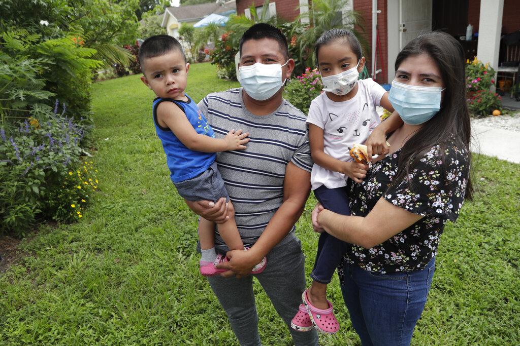 In this Sunday, June 7, 2020, photo, Elbin Sales, second from left, poses for a photograph with his wife, Yecenia Solorzano, right, and children Jordi Sales, left, and Athena Sales, amid the new coronavirus pandemic in Immokalee, Fla. (AP Photo / Lynne Sladky)