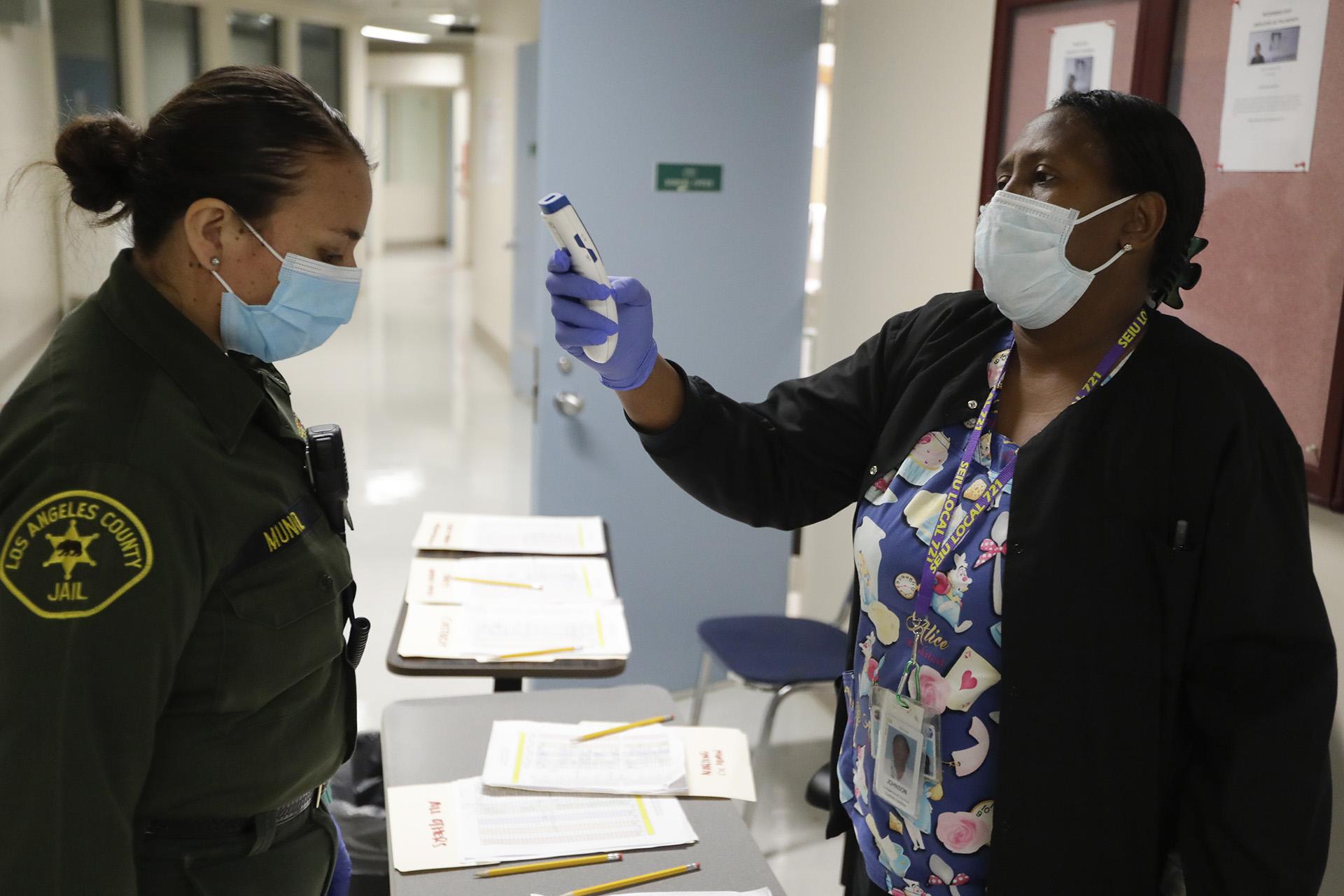 In this April 16, 2020, photo Sonia Munoz, left, custody assistant, gets her temperature taken at the hospital ward of the Twin Towers jail in Los Angeles. (AP Photo / Chris Carlson)