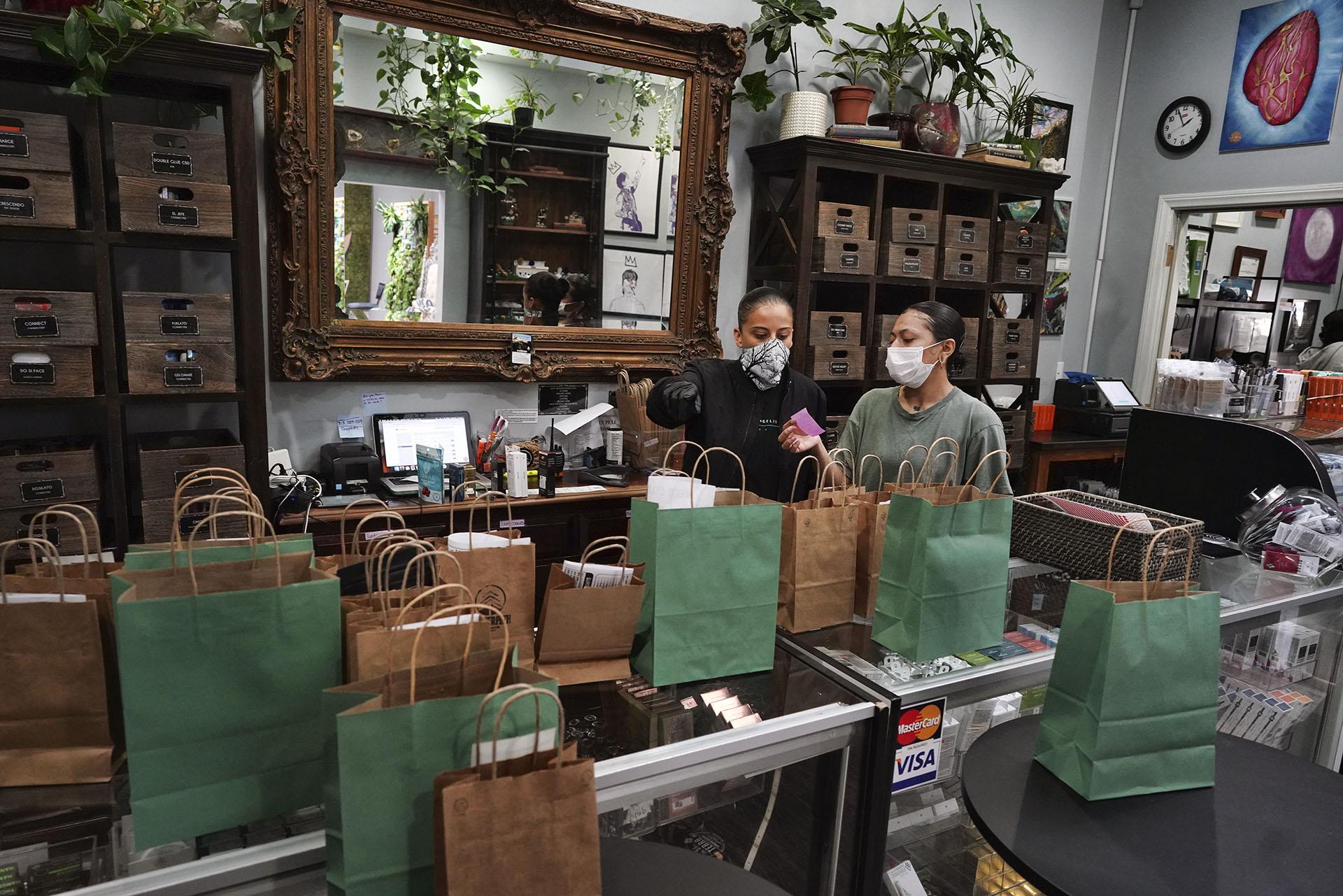 In this Thursday, April 16, 2020, photo, wearing a protective mask and gloves, budtenders prepare orders for customers to pick-up at The Higher Path cannabis dispensary in the Sherman Oaks section of Los Angeles. (AP Photo / Richard Vogel)