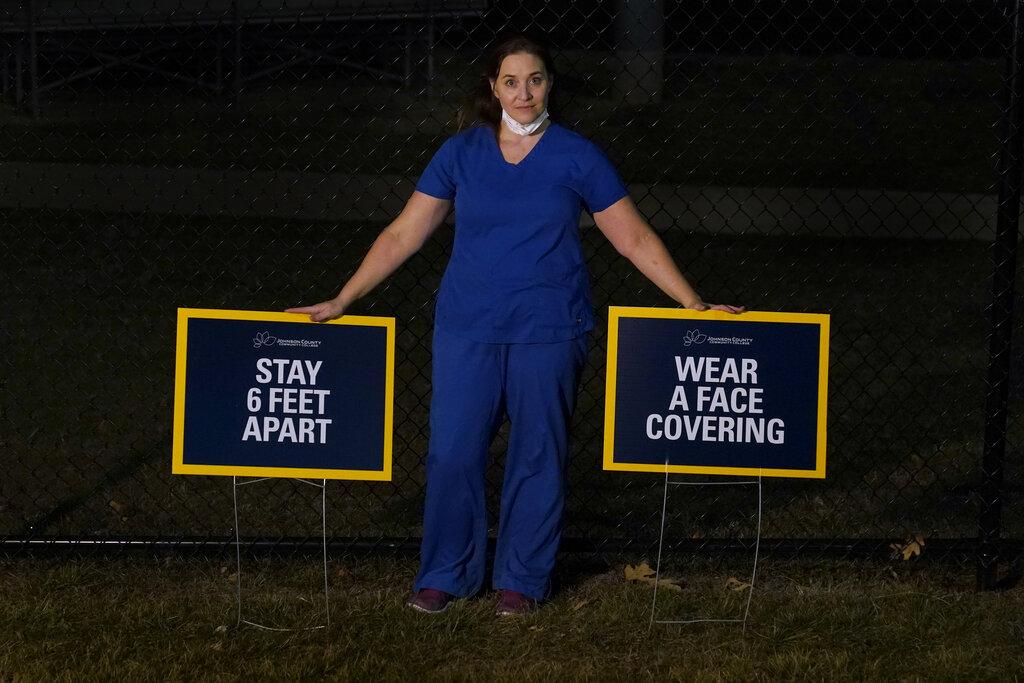 Emergency room nurse L’Erin Ogle poses with coronavirus signs after getting off a 12-hour shift at a nearby hospital where she works Monday, March 8, 2021, in Overland Park, Kan. (AP Photo / Charlie Riedel)