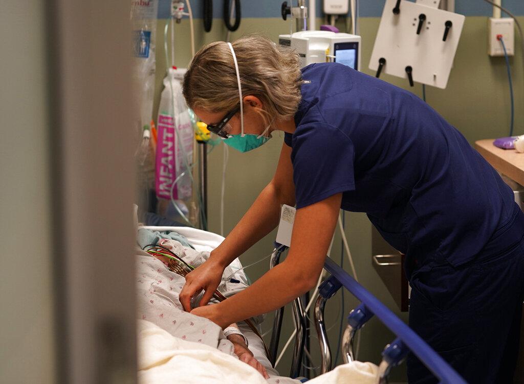 Registered nurse Sandra Younan adjusts an intravenous line for a patient at the emergency room of Providence Cedars-Sinai Tarzana Medical Center in the Tarzana neighborhood of Los Angeles on Thursday, March 11, 2021. (AP Photo / Damian Dovarganes)