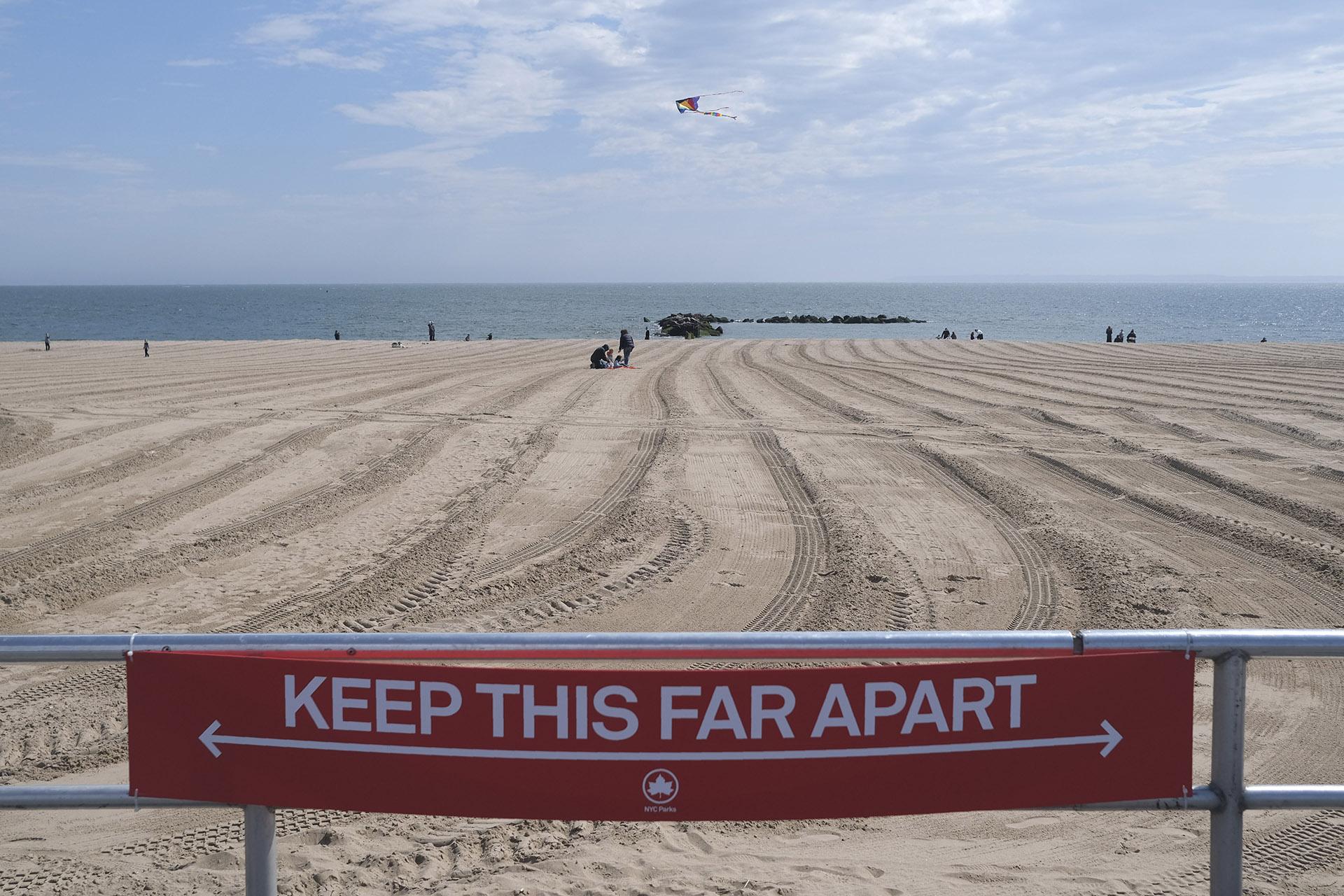In this April 12, 2020, file photo, a sign on the Coney Island boardwalk reminds people to keep their distance in New York. (AP Photo / Seth Wenig, File)