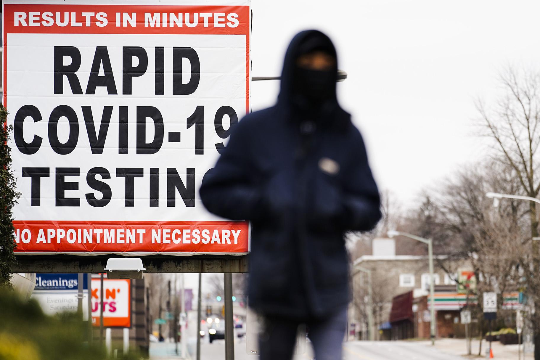 In this Jan. 25, 2021, file photo, a person wearing face mask as a precaution against the coronavirus walks near a sign advertising a rapid COVID-19 testing site in Philadelphia. (AP Photo / Matt Rourke, File)