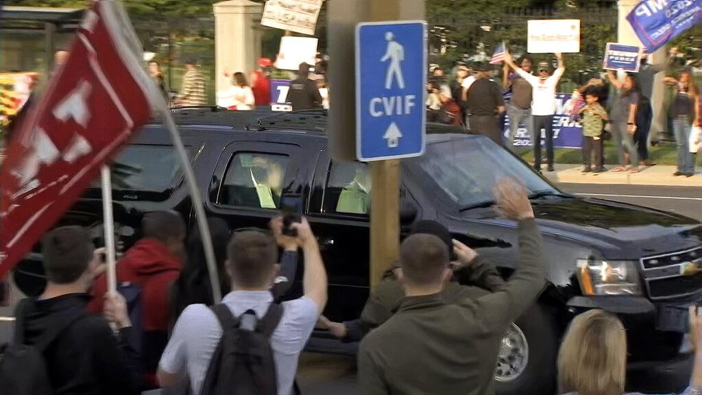 In this image from video, President Donald Trump waves as he drives past supporters gathered outside Walter Reed National Military Medical Center in Bethesda, Md., Sunday, Oct. 4, 2020. (AP Photo / Carlos Vargas)