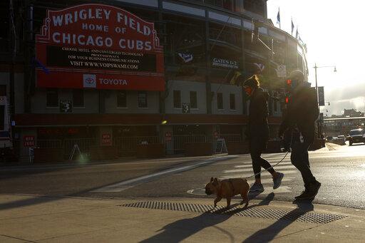 People walk their dog outside of Wrigley Field on opening day for the Chicago Cubs, Thursday, April 1, 2021, in Chicago. (AP Photo / Shafkat Anowar)