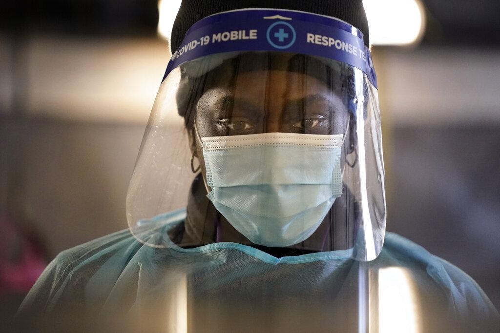In this Dec. 8, 2020, file photo, a health care worker wears personal protective equipment as she speaks to a patient at a mobile testing location for COVID-19 in Auburn, Maine. (AP Photo / Robert F. Bukaty, File)