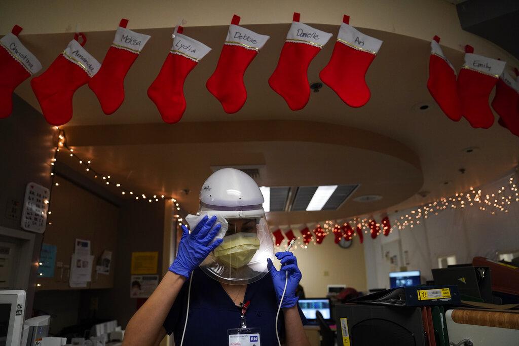Registered nurse Romina Pacheco disinfects her powered air purifying respirator after tending to a patient in a COVID-19 unit decorated with Christmas stockings with nurses’ names written on them at Mission Hospital in Mission Viejo, Calif., Monday, Dec. 21, 2020. (AP Photo / Jae C. Hong)
