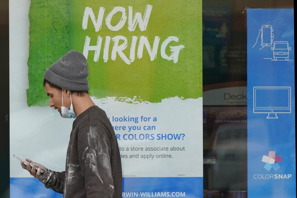 A man walks past a “Now Hiring” sign on a window at Sherwin Williams store, Friday, Feb. 26, 2021, in Woodmere Village, Ohio. (AP Photo / Tony Dejak)