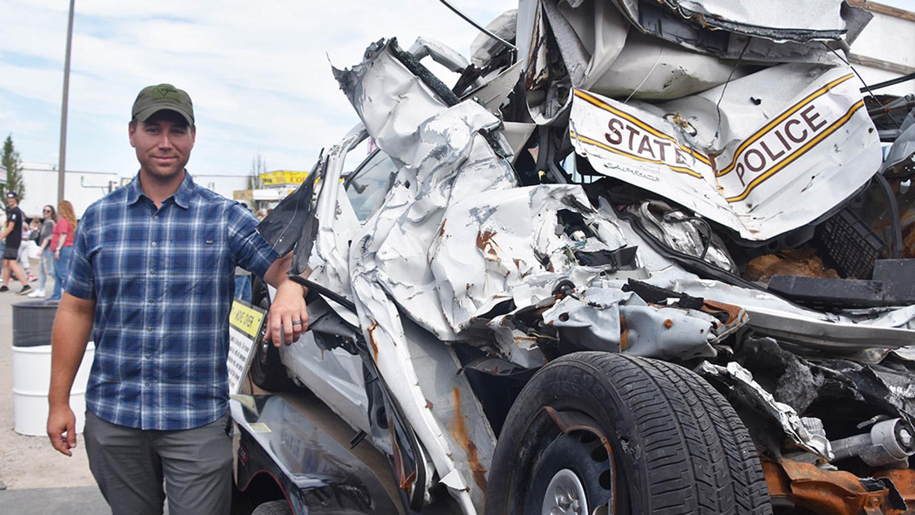 Trooper Alex Womack stands beside his wrecked squad. Womack sustained arm, leg and back injuries and required more than a year off work to recover. (Courtesy of Illinois State Police)