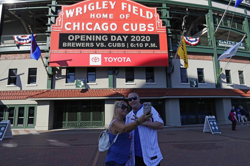 Sandra Bilger, left, and Dustin Moore take a photo in front of the marquee at Wrigley Field before an opening day baseball game between the Chicago Cubs and the Milwaukee Brewers in Chicago, Friday, July 24, 2020, in Chicago. (AP Photo / Nam Y. Huh)