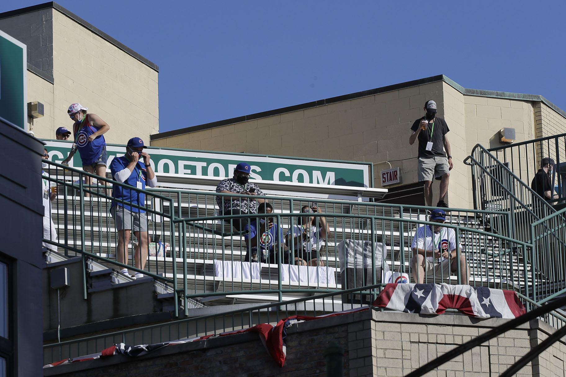 Chicago Cubs fans look to the field from a nearby rooftop before an opening day baseball game between the Chicago Cubs and the Milwaukee Brewers in Chicago, Friday, July 24, 2020, in Chicago. (AP Photo / Nam Y. Huh)