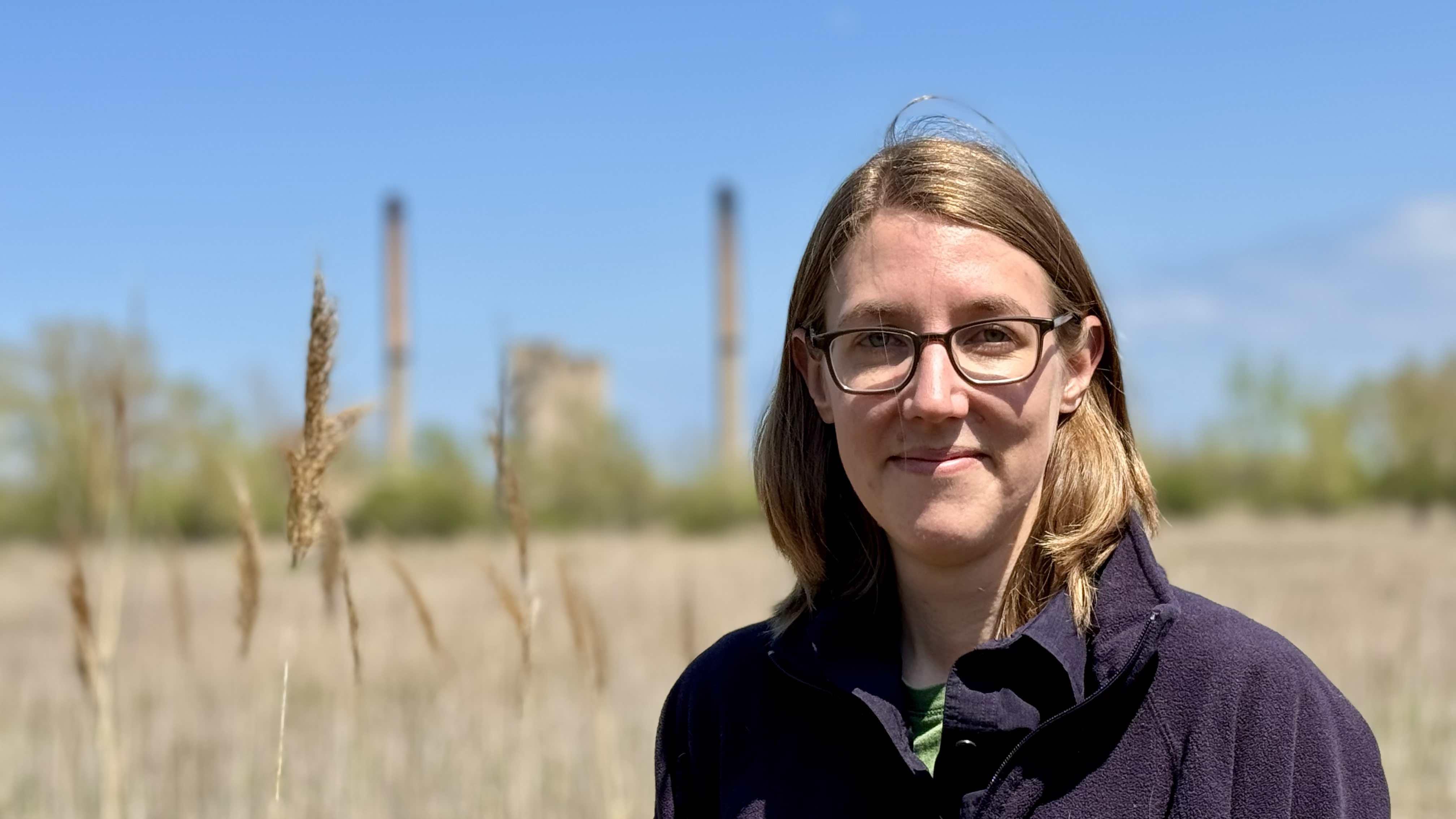 Researcher Melissa Youngquist at Big Marsh Park on Chicago's Southeast Side, where distant smokestacks are a reminder of the Calumet region's industrial use. (Patty Wetli / WTTW News)