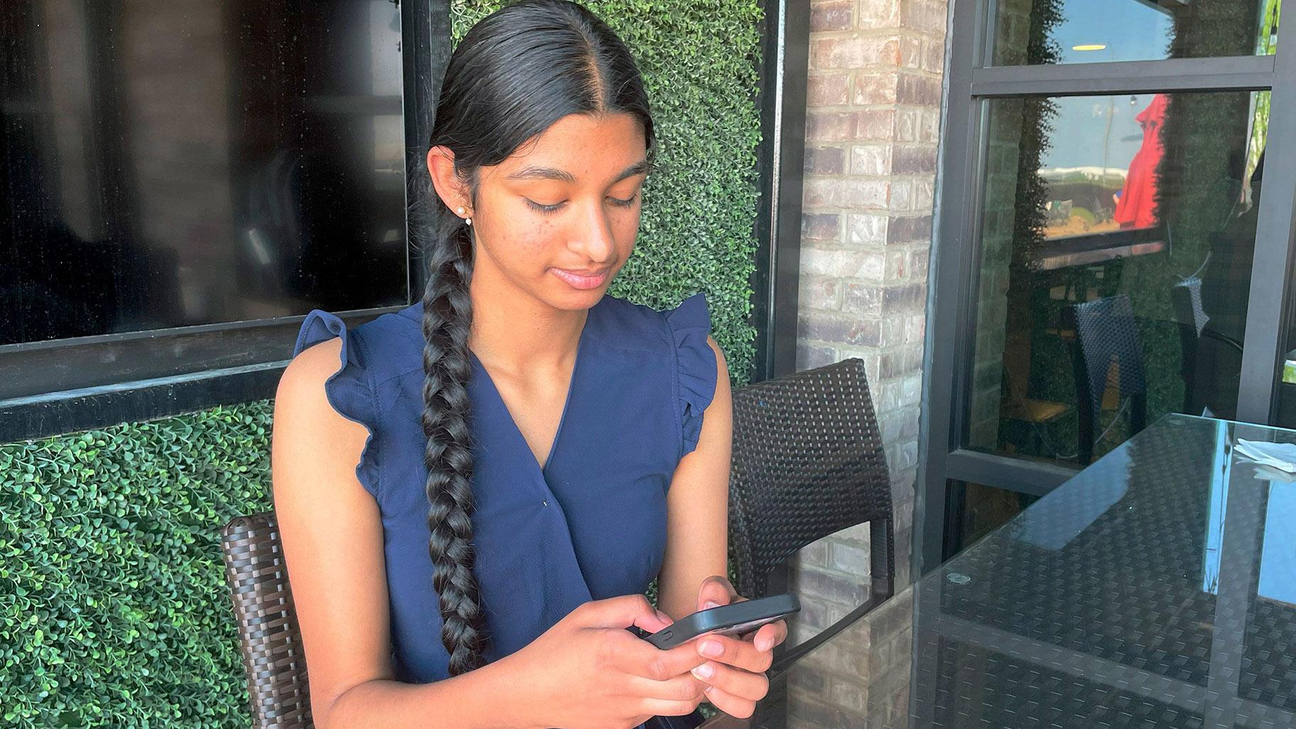 Shreya Nallamothu looks at her phone in May 2023 in Bloomington, Illinois. The teenager was instrumental in persuading Illinois lawmakers to pass a law creating protections for child social media influencers. (Claire Savage / AP via CNN Newsource)