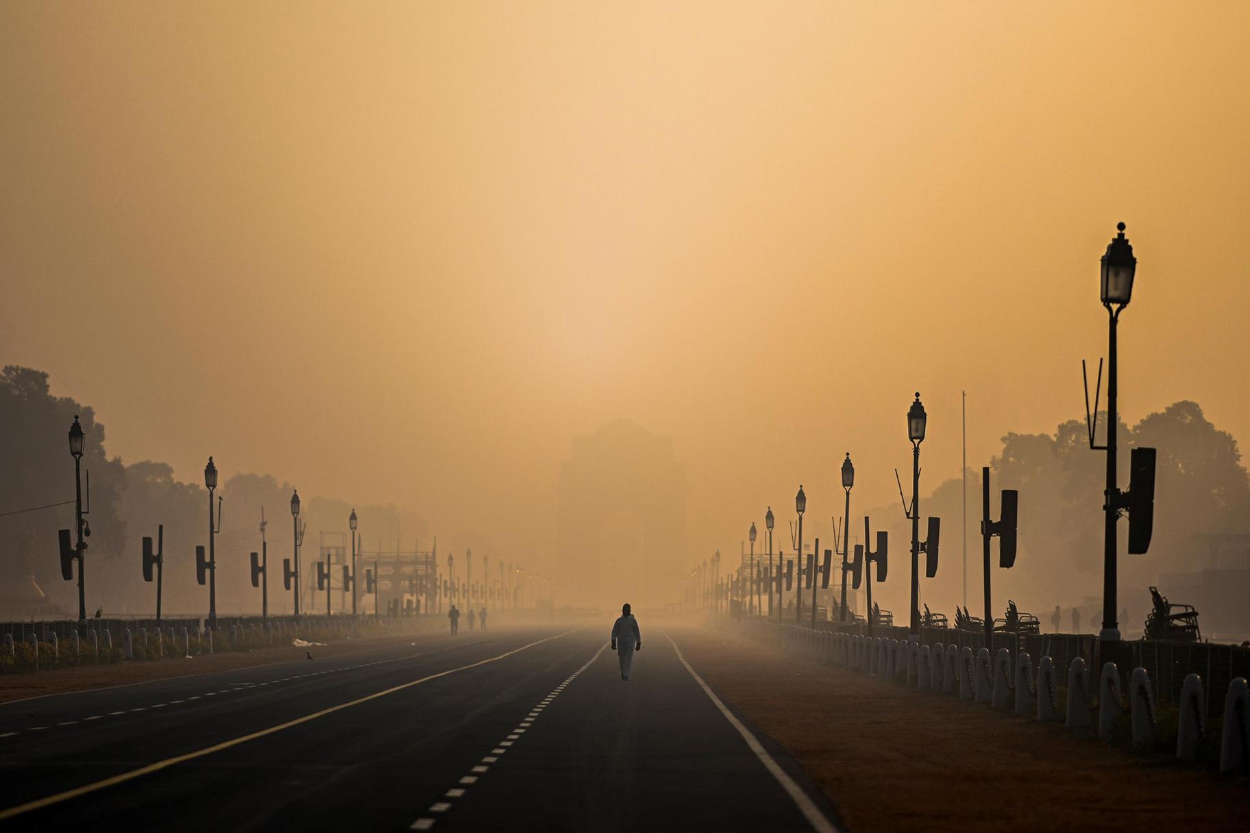 A man walks along Rajpath amid smoggy conditions in New Delhi on Jan. 28. Air pollution is shaving nearly six years off people's lives in the country, on average. (Jewel Samad / AFP / Getty Images)