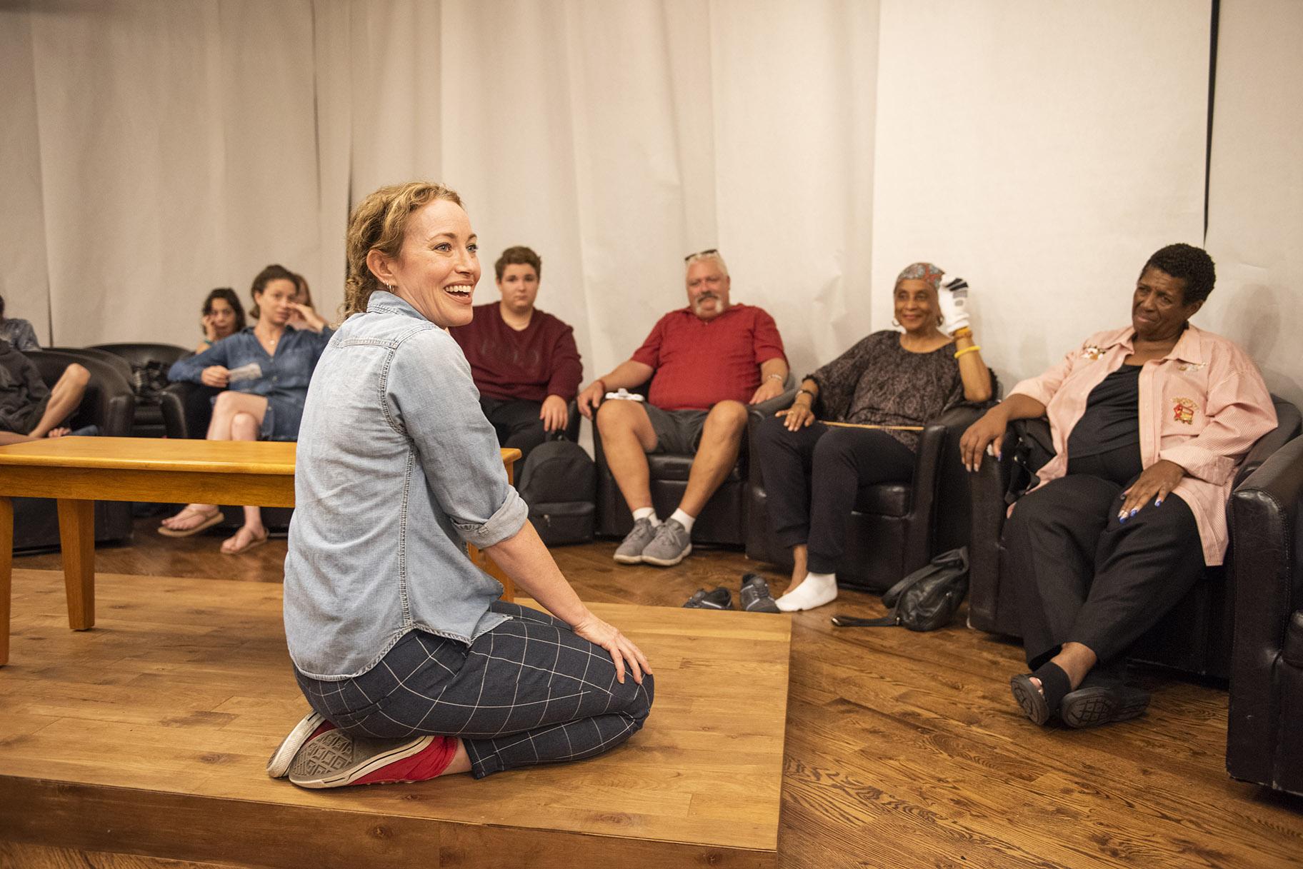 Rebecca Spence sits on a tabletop with audience members in “Every Brilliant Thing.” (Photo credit: Michael Brosilow)