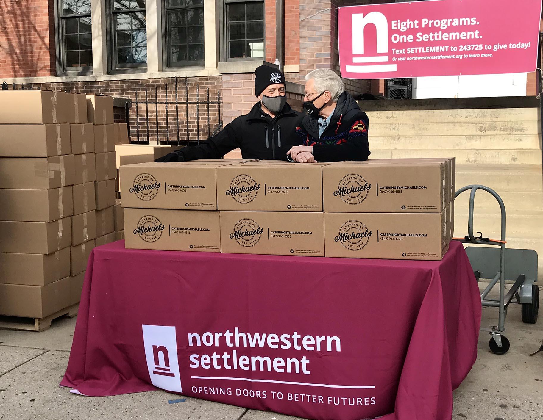 Stewart Glass, left, president of Catering by Michaels, and Ron Manderschied, president of Northwestern Settlement, stand with some of the Thanksgiving boxes before handing them out to the community. (Ariel Parrella-Aureli / WTTW News)