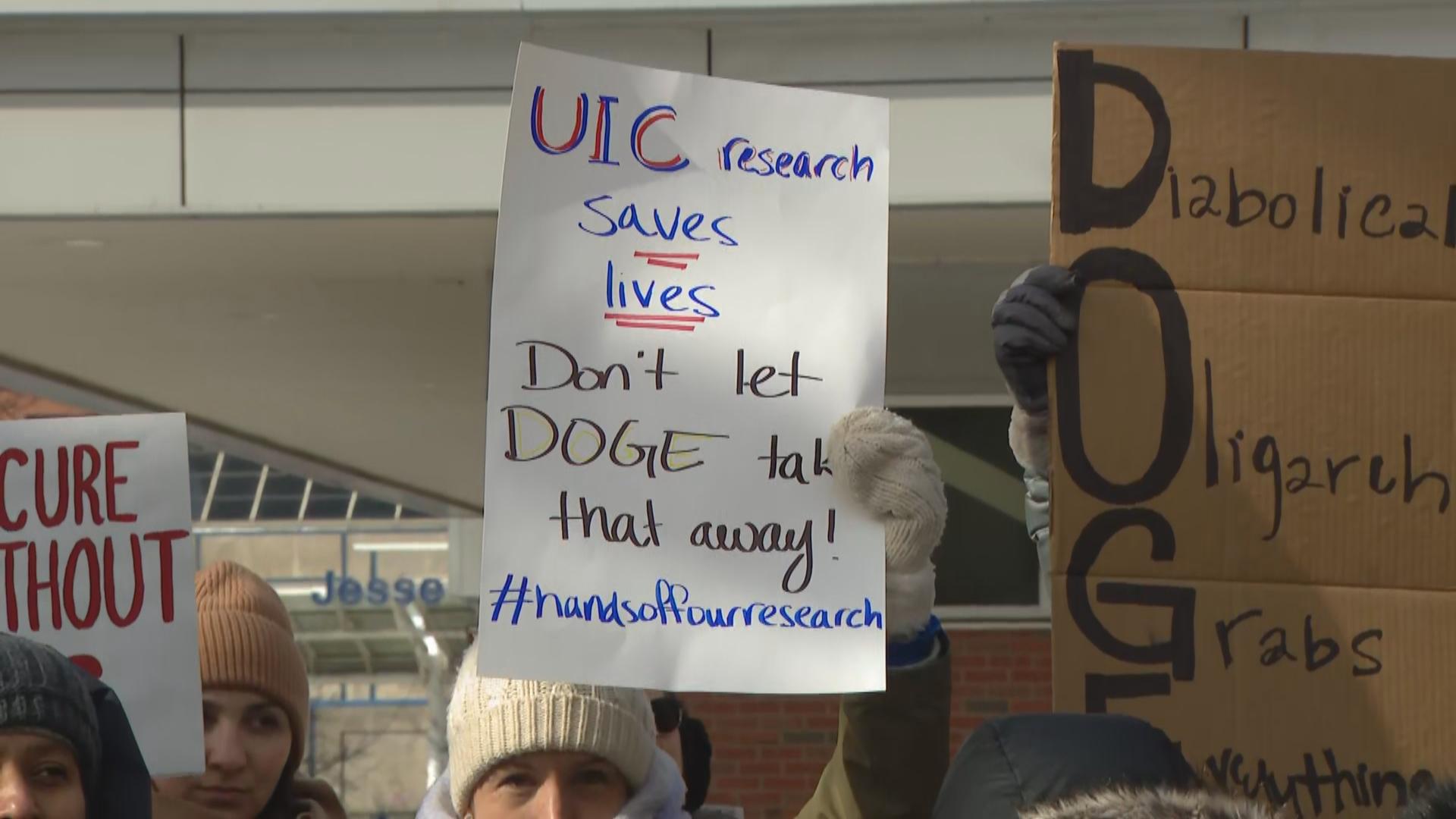 University of Illinois Chicago faculty hold signs denouncing possible federal funding cuts during a rally at the school on Feb. 19, 2025. (WTTW News)