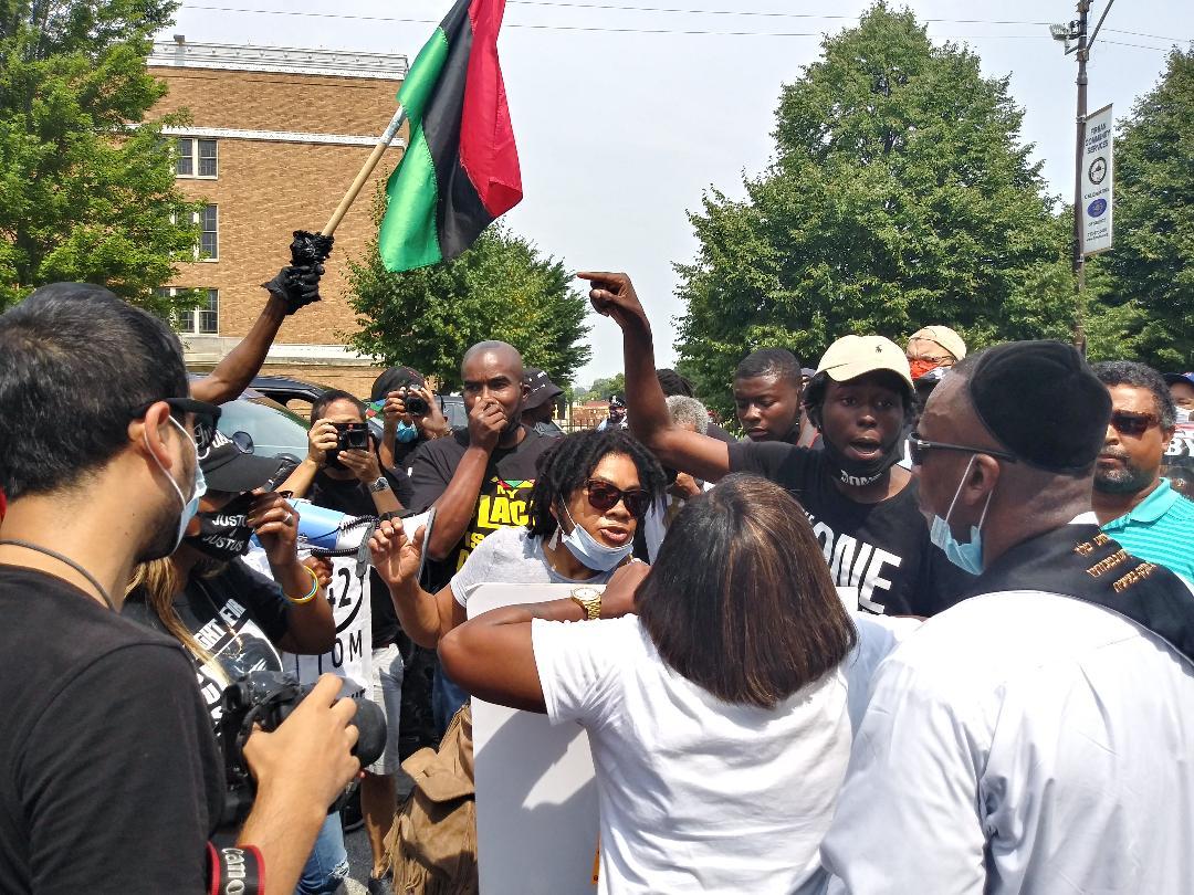 Counterprotesters appear on the scene, led by Yashua Aton (center, in black and yellow T-shirt), of the Original Men in Black. (Annemarie Mannion / WTTW News)