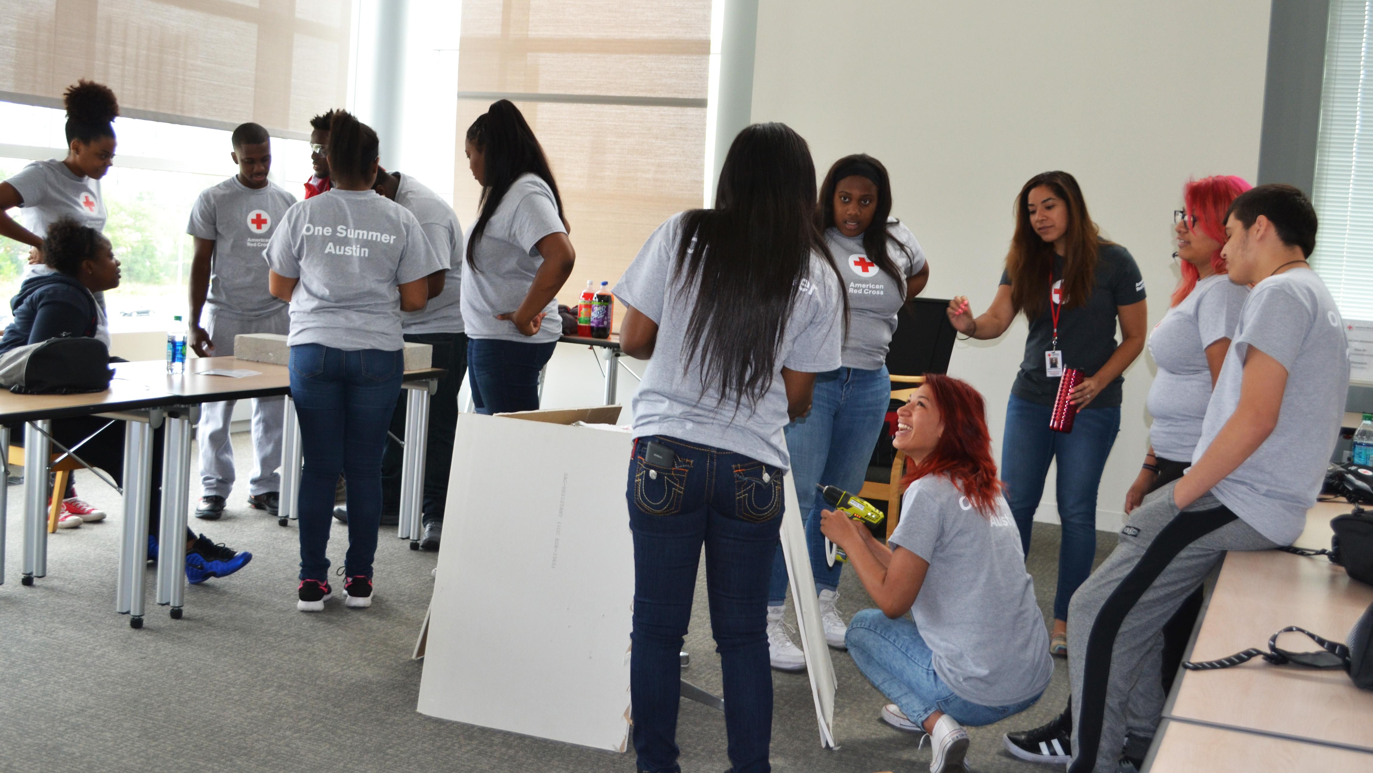 Young adults practice installing smoke detectors on a piece of dry wall. (Maya Miller / Chicago Tonight)