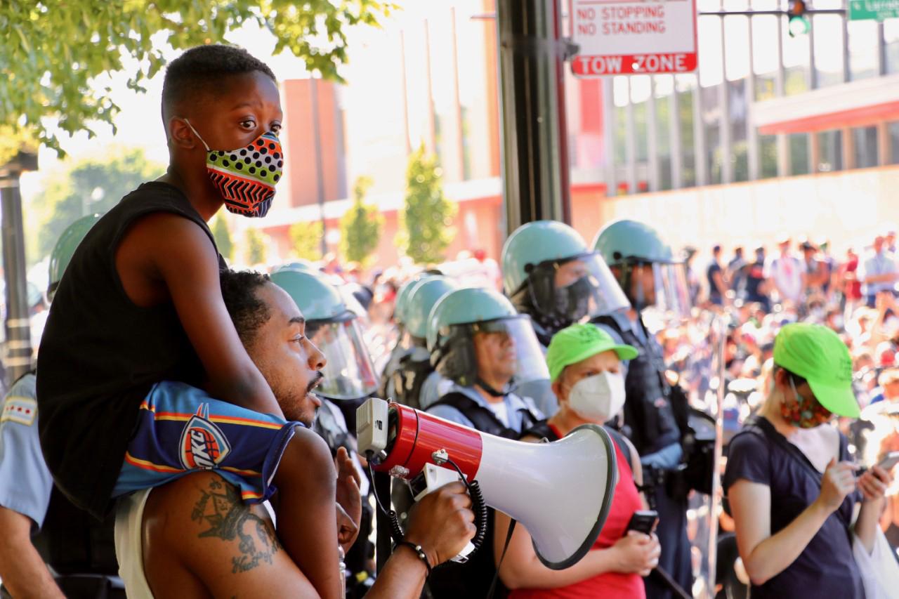 Jahan James, 8, sits on the shoulders of his father, Jonathan James, who addresses the crowd during a protest on Tuesday, June 2, 2020 in Old Town. (Evan Garcia / WTTW News)