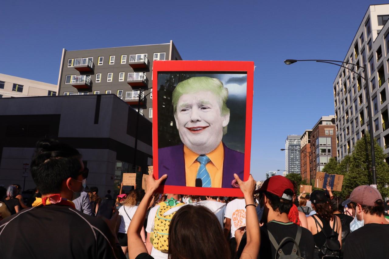 A woman marching in the North Side protests on June 2, 2020 holds a sign of President Donald Trump depicted as The Joker. (Evan Garcia / WTTW News)