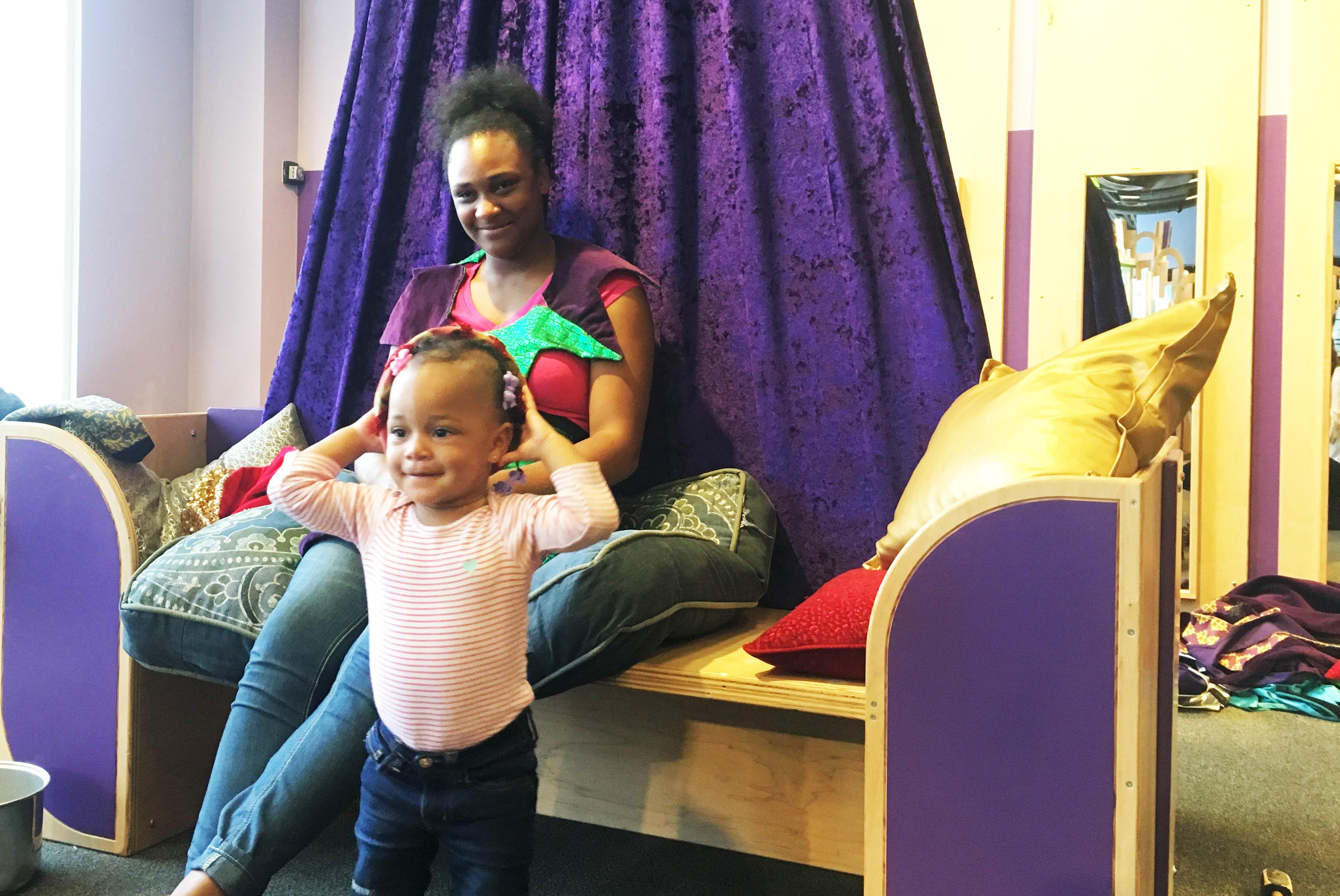Keyana Hopkins, 18, watches her 1-year-old daughter play dress-up at the Chicago Children's Museum “Once Upon a Castle” exhibit. (Maya Miller / Chicago Tonight)