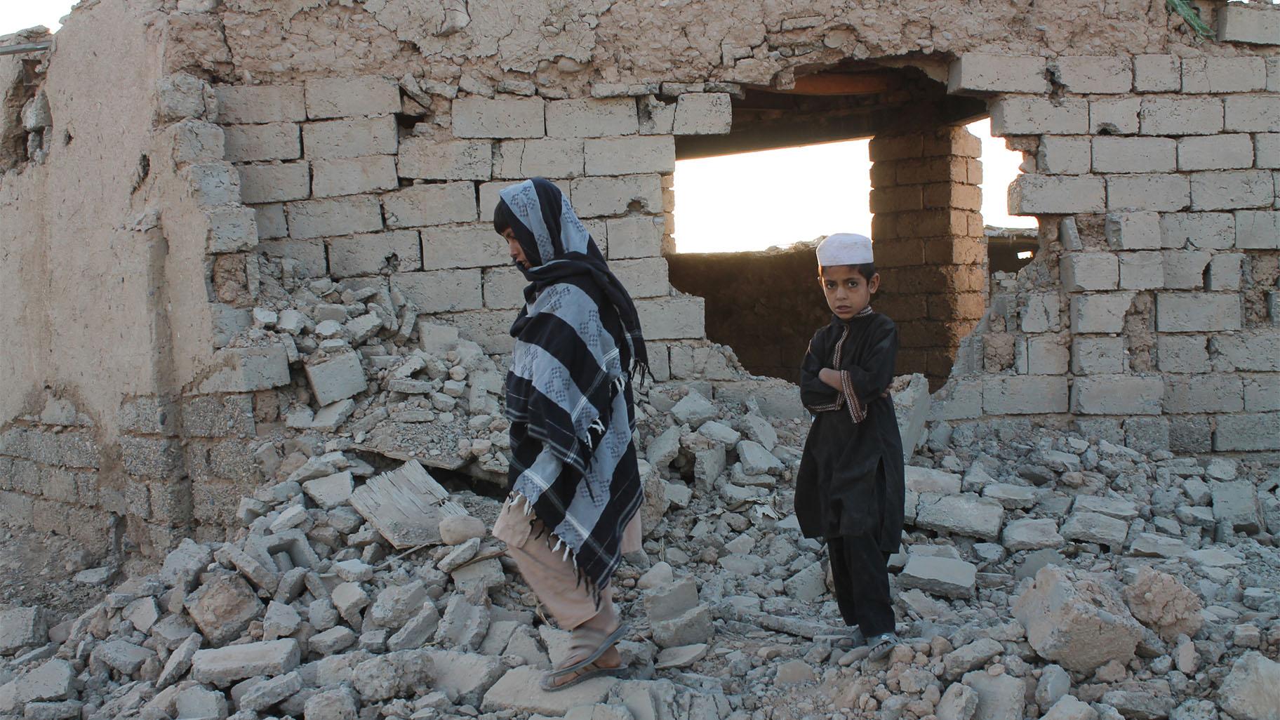 Afghan boys walk near a damaged house after airstrikes in two weeks ago during a fight between government forces and the Taliban in Lashkar Gah, Helmand province, southwestern, Afghanistan, Saturday, Aug. 21, 2021. (AP Photo / Abdul Khaliq)