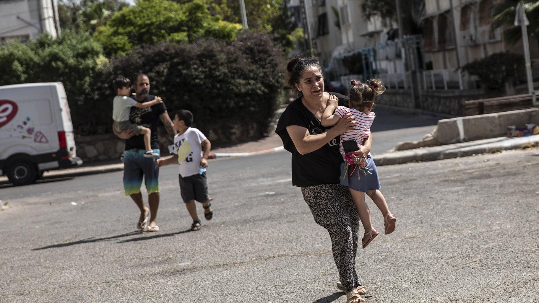 Lia Tal, 40, rushes with her children and partner to take shelter as a siren sounds a warning of incoming rockets fired from the Gaza Strip, In Ashdod, Israel, Thursday, May 20, 2021. (AP Photo / Heidi Levine)