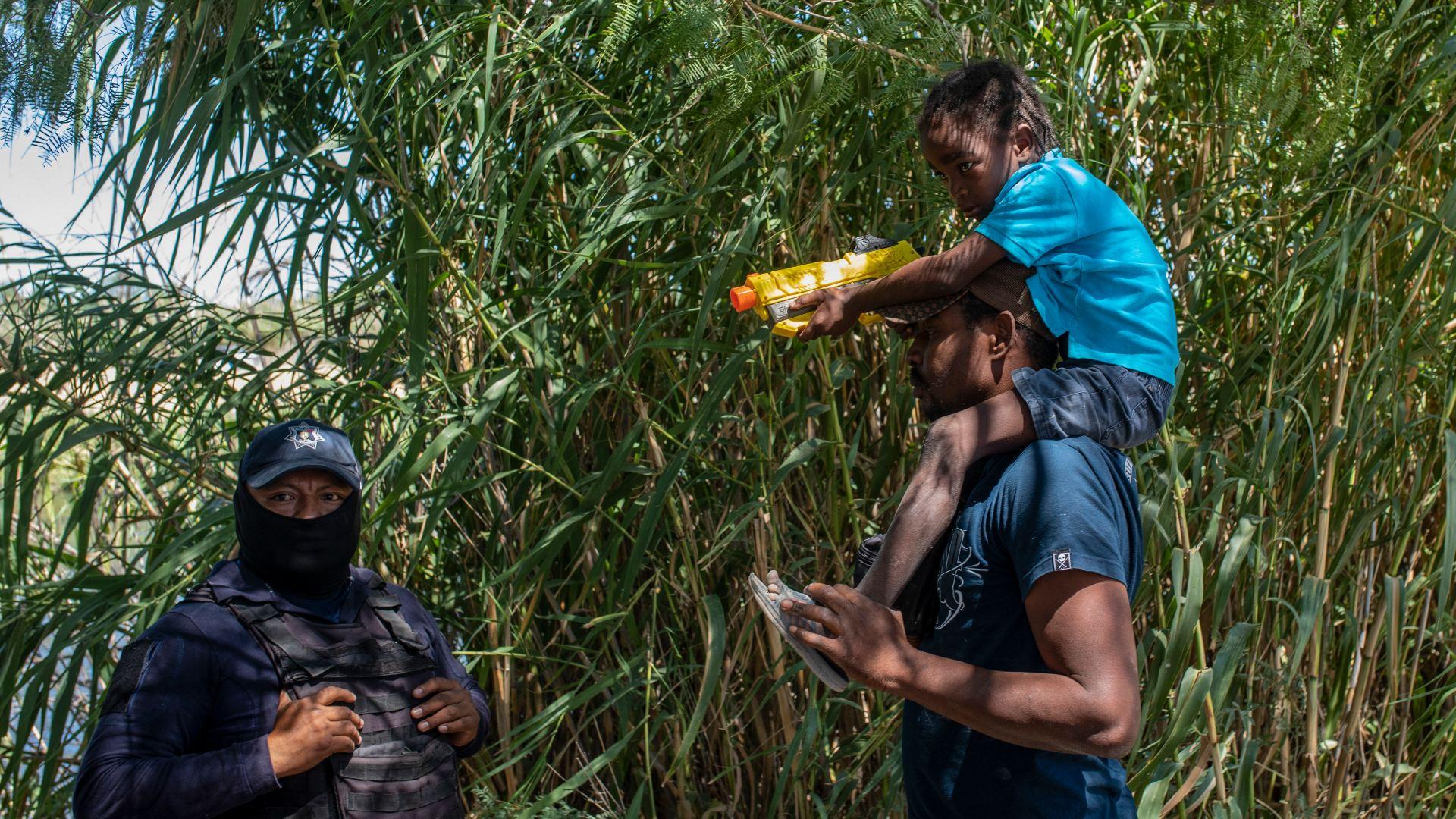 A Haitian migrant talks to with a Mexican police officer blocking access to the Rio Grande river so that immigrants can't use it to cross the U.S.-Mexico border from Ciudad Acuna, Mexico, Thursday, Sept. 23, 2021. (AP Photo / Felix Marquez)