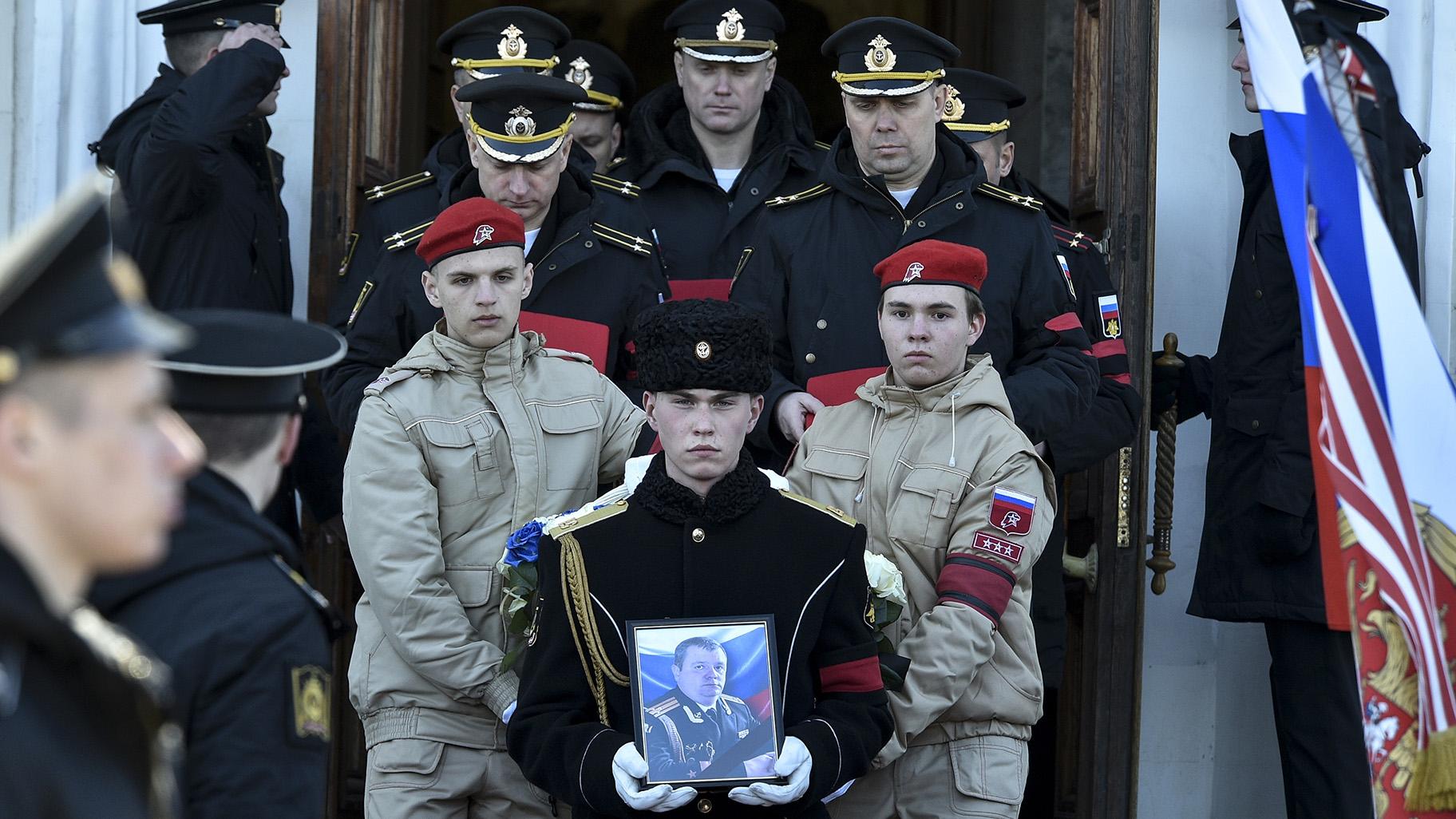 A serviceman carries the photo of Capt. Andrei Paliy, a deputy commander of Russia's Black Sea Fleet, during a farewell ceremony in Sevastopol, Crimea, Wednesday, March 23, 2022. Paliy was killed in action during fighting with Ukrainian forces in the Sea of Azov port of Mariupol. (AP Photo)