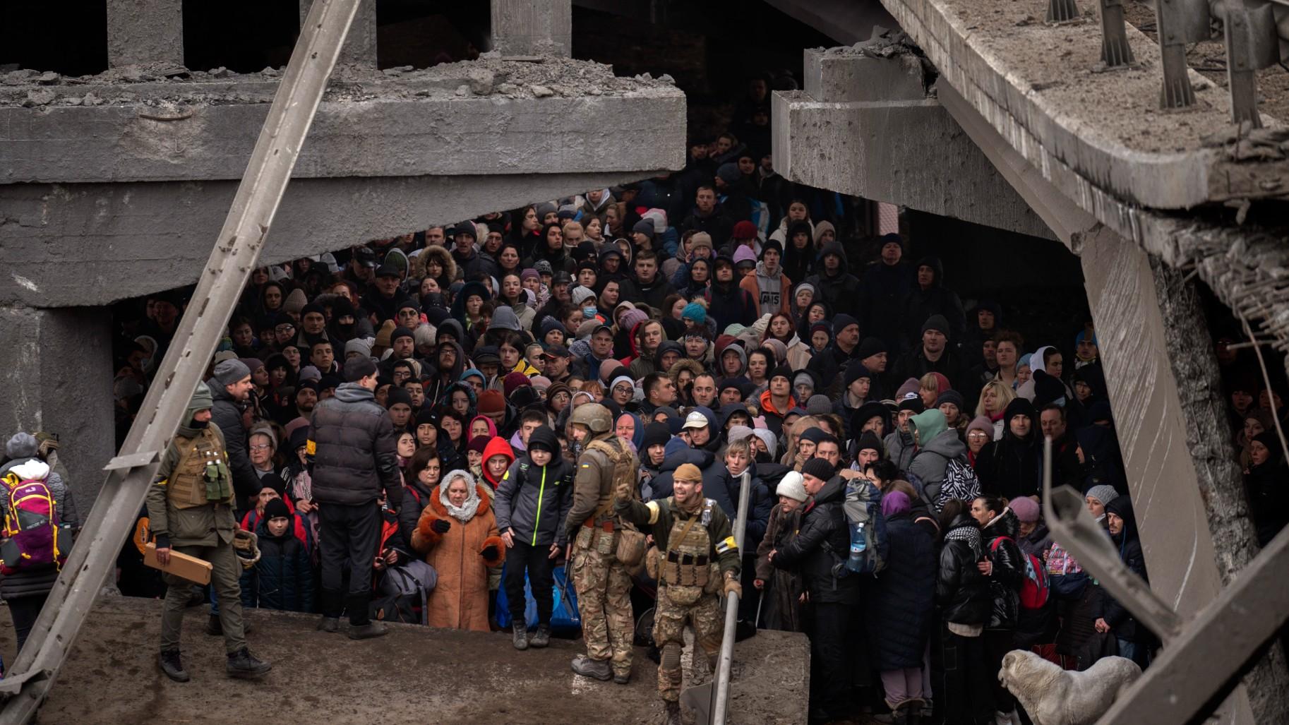   Ukrainians crowd under a destroyed bridge as they try to flee crossing the Irpin river in the outskirts of Kyiv, Ukraine, Saturday, March 5, 2022. (AP Photo / Emilio Morenatti)