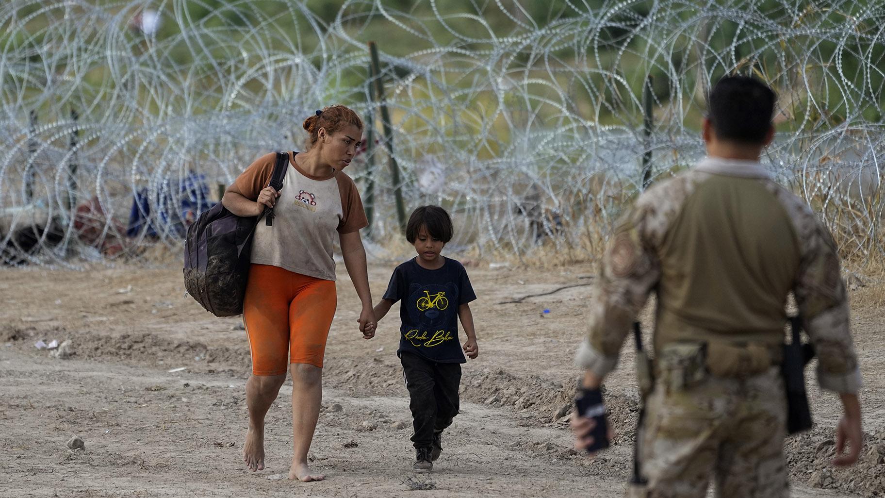 Migrants who crossed into the U.S. from Mexico walk past concertina wire lining the banks of the Rio Grande as they move to an area for processing, Sept. 21, 2023, in Eagle Pass, Texas. Migrants have always come to the U.S., but the immigration system now seems strained nationwide more than ever. (AP Photo / Eric Gay)