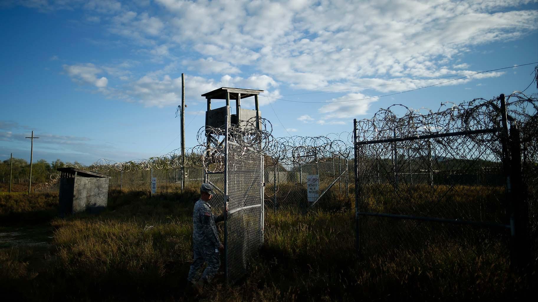 In this Nov. 21, 2013, file photo reviewed by the U.S. military, a soldier closes the gate at the now abandoned Camp X-Ray, which was used as the first detention facility for al-Qaida and Taliban militants who were captured after the Sept. 11 attacks at Guantanamo Bay Naval Base, Cuba. (AP Photo / Charles Dharapak, File)