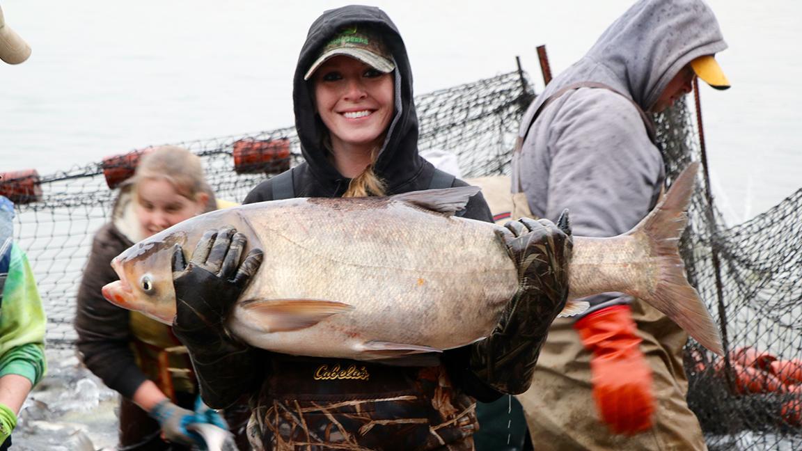 Charmayne Anderson holds a large Bighead carp caught in a lake in Morris, Illinois, in 2017. (Evan Garcia / WTTW News)