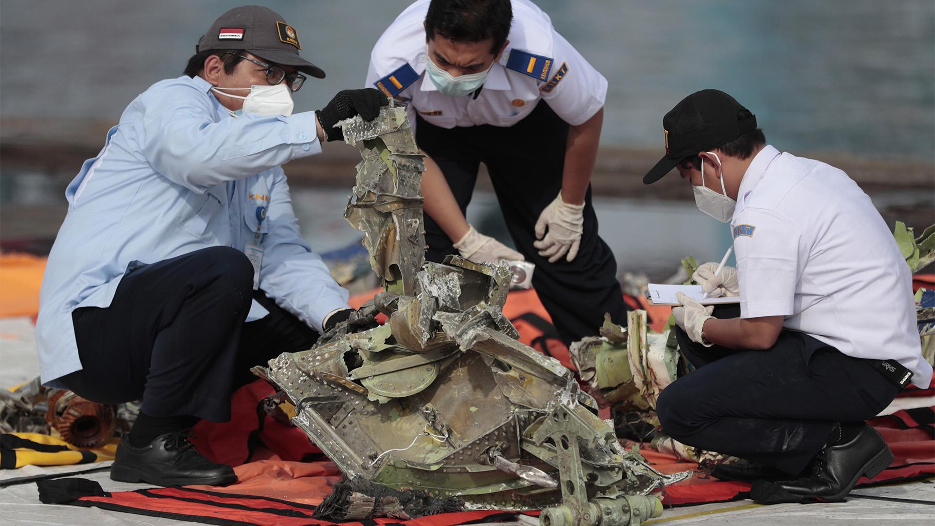 In this Jan. 21, 2021, file photo, investigators inspect a pieces of the Sriwijaya Air flight SJ-182 retrieved from the Java Sea where the passenger jet crashed on Jan. 9, at Tanjung Priok Port in Jakarta, Indonesia. A lawsuit filed in Seattle against Boeing alleges a malfunctioning autothrottle system on the older 737 jet led to the January crash of the Sriwijaya Air flight that killed all 62 people on board. (AP Photo / Dita Alangkara, File)