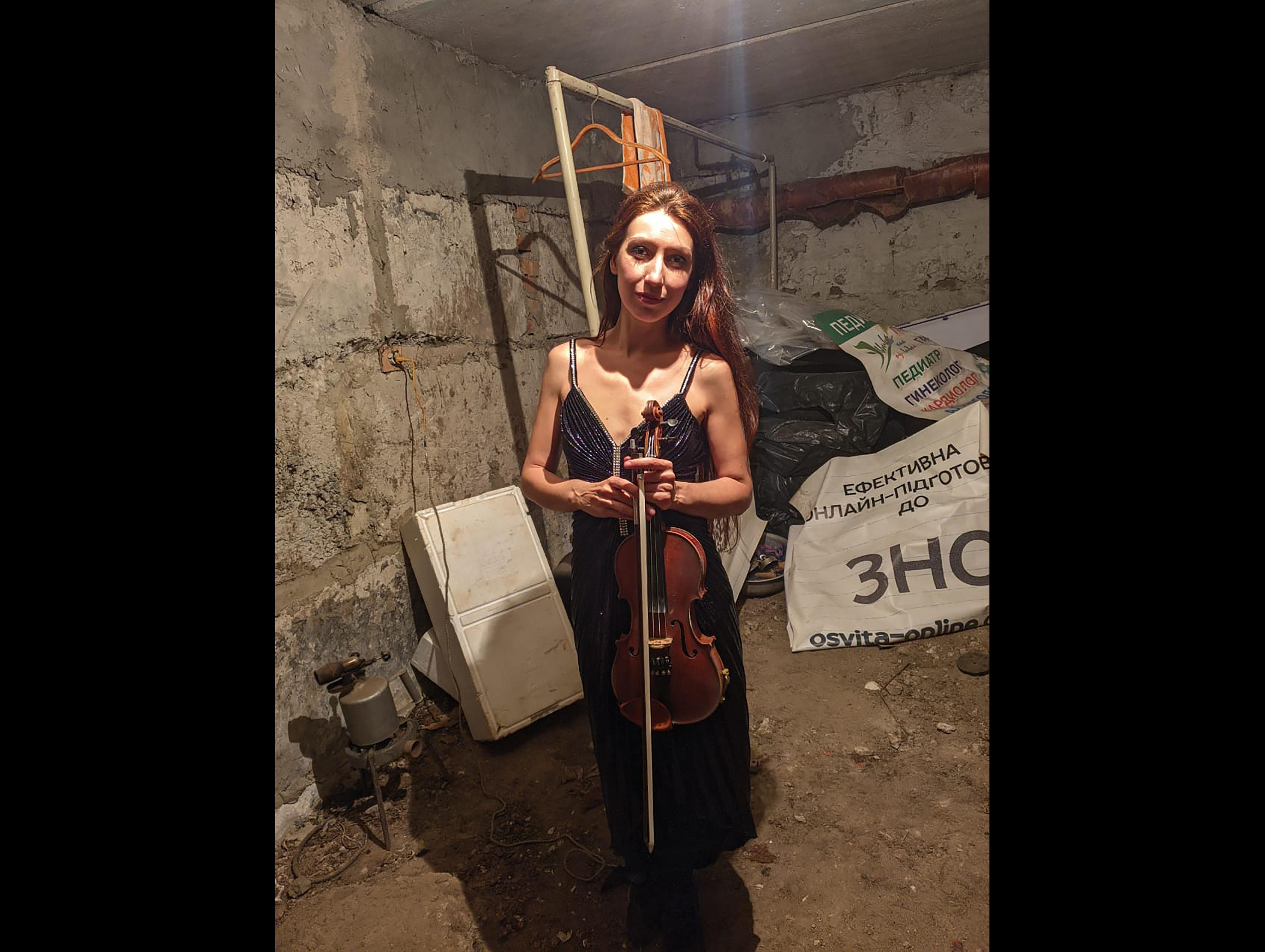 Vera Lytovchenko holds her violin as she poses for a photo in a basement of an apartment building in Kharkiv, Ukraine, Sunday March 6, 2022. (Vera Lytovchenko via AP)