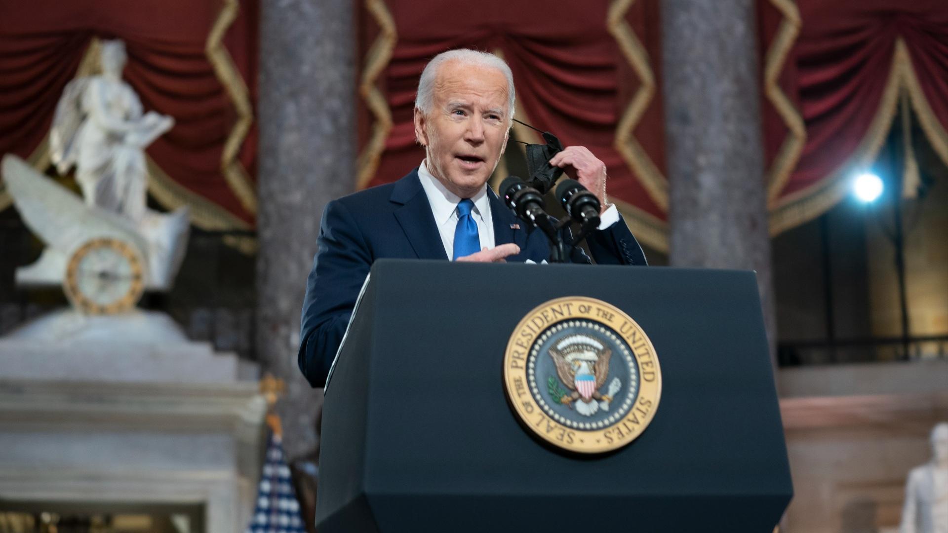 President Joe Biden takes off his face mask as he speaks from Statuary Hall at the U.S. Capitol to mark the one-year anniversary of the Jan. 6 riot at the Capitol by supporters loyal to then-President Donald Trump, Thursday, Jan. 6, 2022, in Washington. (Greg Nash / Pool via AP)