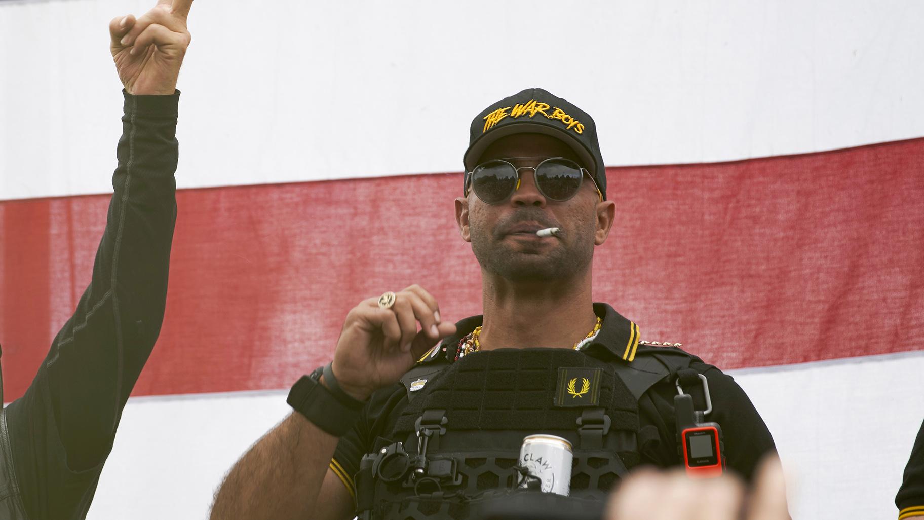 Proud Boys leader Enrique Tarrio wears a hat that says The War Boys and smokes a cigarette at a rally in Delta Park on Sept. 26, 2020, in Portland, Ore. (AP Photo / Allison Dinner, File)