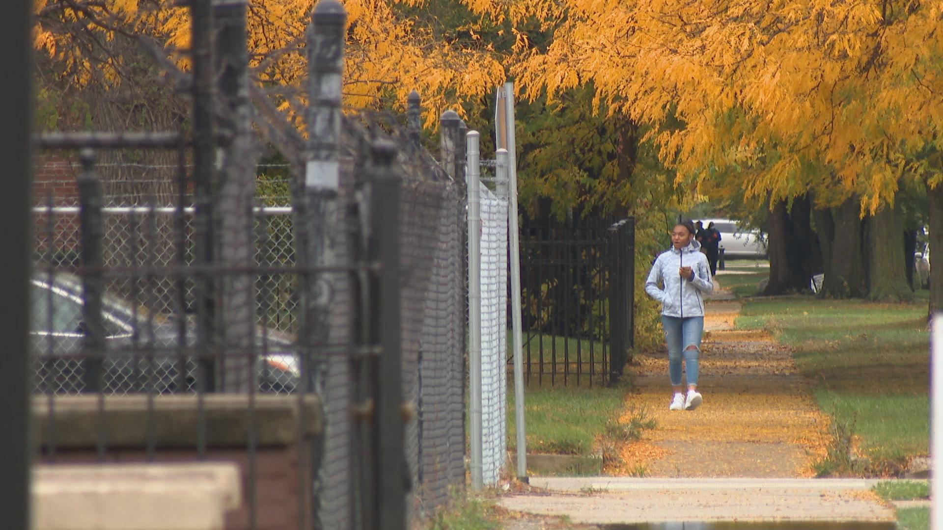 A pedestrian walks along a tree-lined street in Chicago on Oct. 12, 2020. As fall arrives, the state is entering its ninth month of a pandemic that has infected nearly 325,000 Illinois residents. (WTTW News)