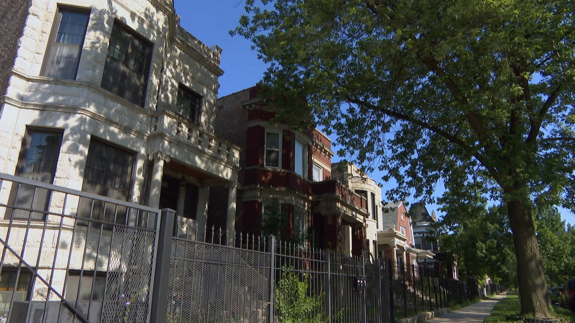 In this file photo, houses sit behind metal fencing on a tree-lined street in Chicago. (WTTW News)