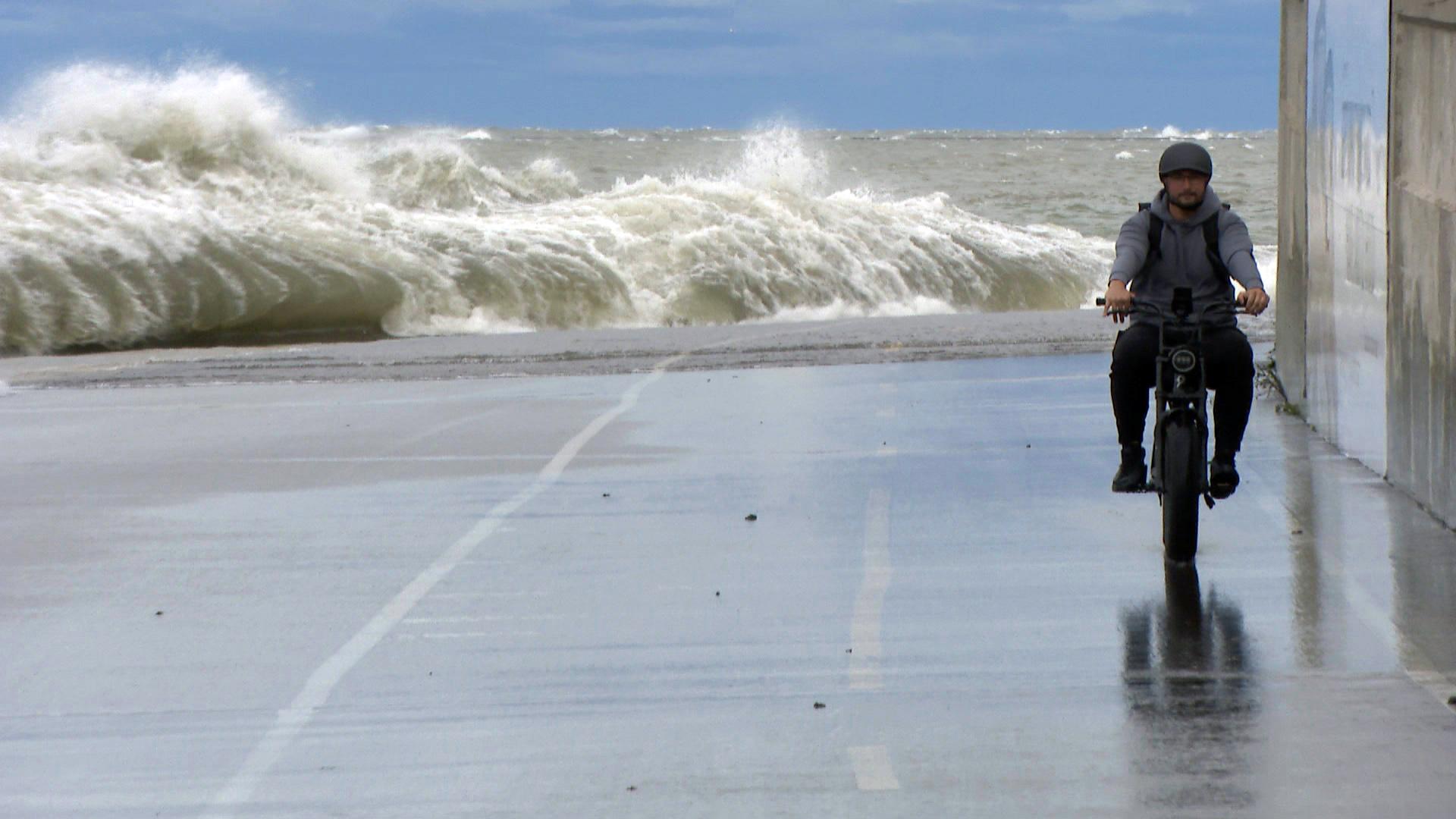 A man rides a bike along a wave-battered lakefront in Chicago on Wednesday, Sept. 22, 2021. (WTTW News)
