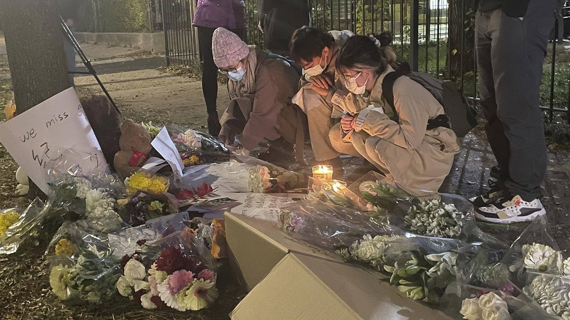 Students and friends of Shaoxiong "Dennis" Zheng stop by a memorial on Wednesday, Nov. 10, 2021 in Chicago.  (Madeline Kenney / Chicago Sun-Times via AP)