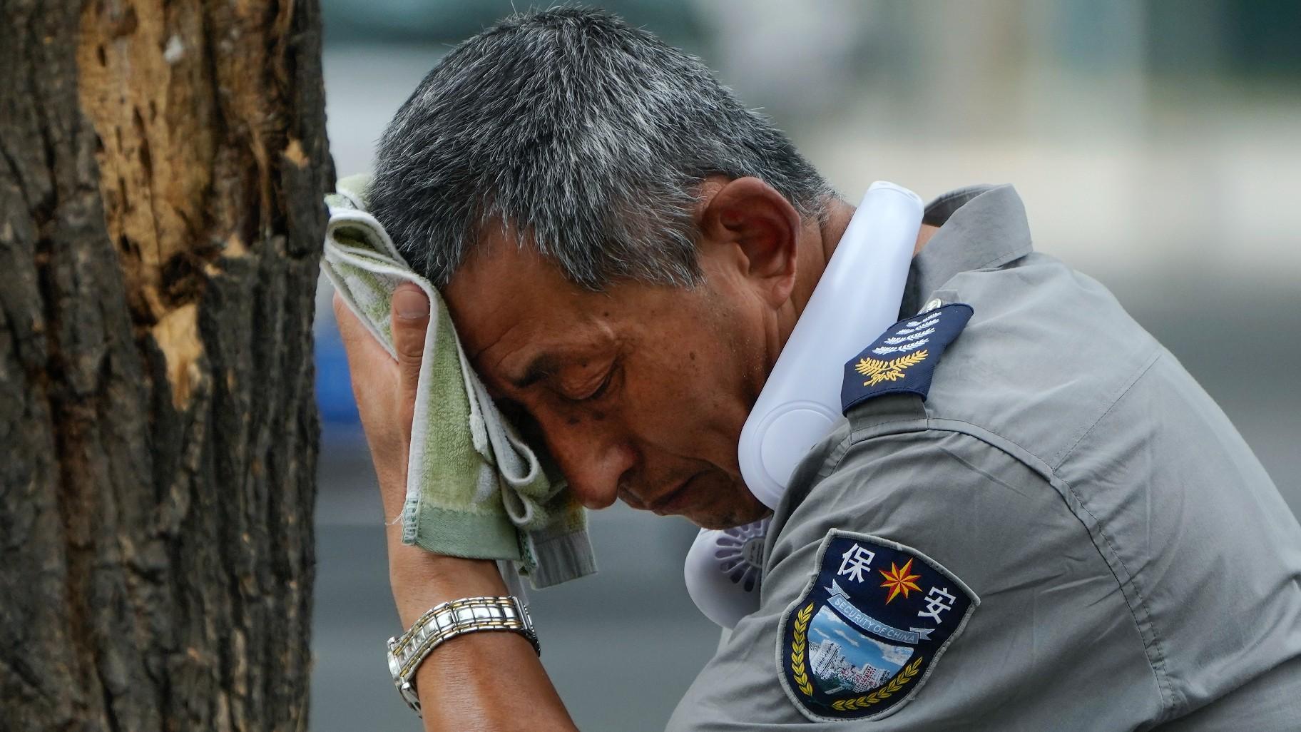 A security guard wearing an electric fan on his neck wipes his sweat on a hot day in Beijing, Monday, July 3, 2023. (AP Photo / Andy Wong) A security guard wearing an electric fan on his neck wipes his sweat on a hot day in Beijing, Monday, July 3, 2023. (AP Photo / Andy Wong)