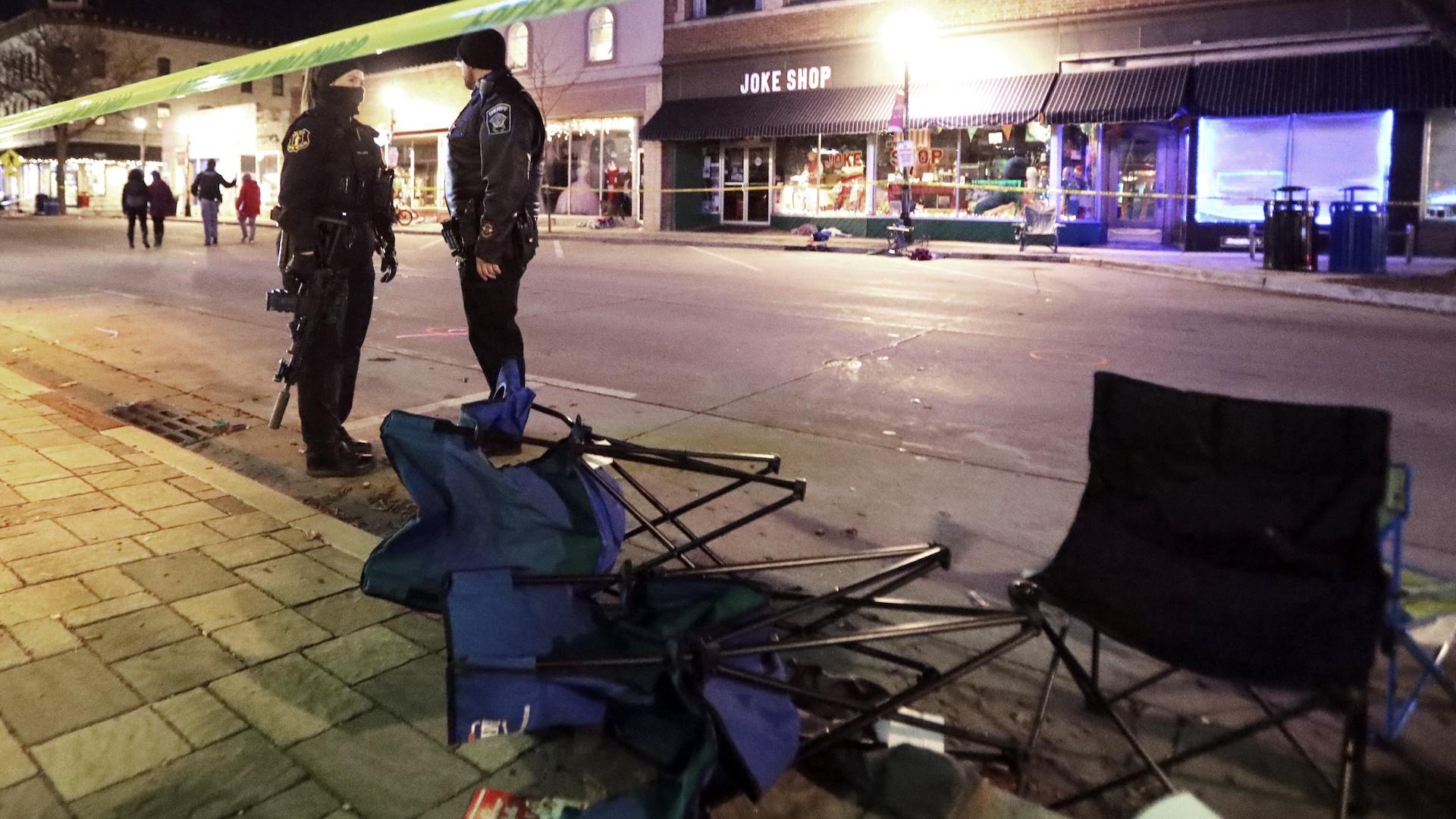Police stand near toppled chairs lining W. Main St. in downtown Waukesha, Wis., after an SUV drove into a parade of Christmas marchers, Sunday, Nov. 21, 2021. (John Hart/Wisconsin State Journal via AP)