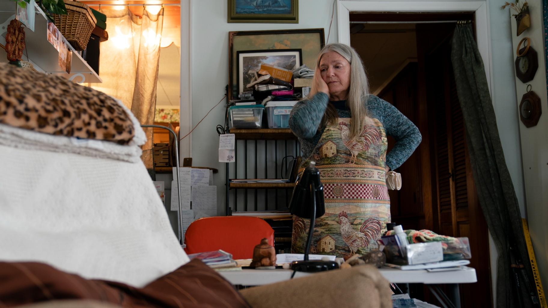 FILE - Nancy Rose, who contracted COVID-19 in 2021 and exhibits long-haul symptoms including brain fog and memory difficulties, pauses while organizing her desk space, Tuesday, Jan. 25, 2022, in Port Jefferson, N.Y. Rose, 67, said many of her symptoms waned after she got vaccinated, though she still has bouts of fatigue and memory loss. (John Minchillo / AP Photo, File)