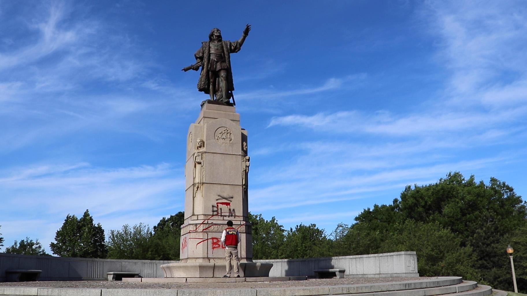 Courtney Johnson, a South Side resident, stands in front of a vandalized statue of Christopher Columbus in Grant Park on Saturday, June 15, 2020. (Evan Garcia / WTTW News)