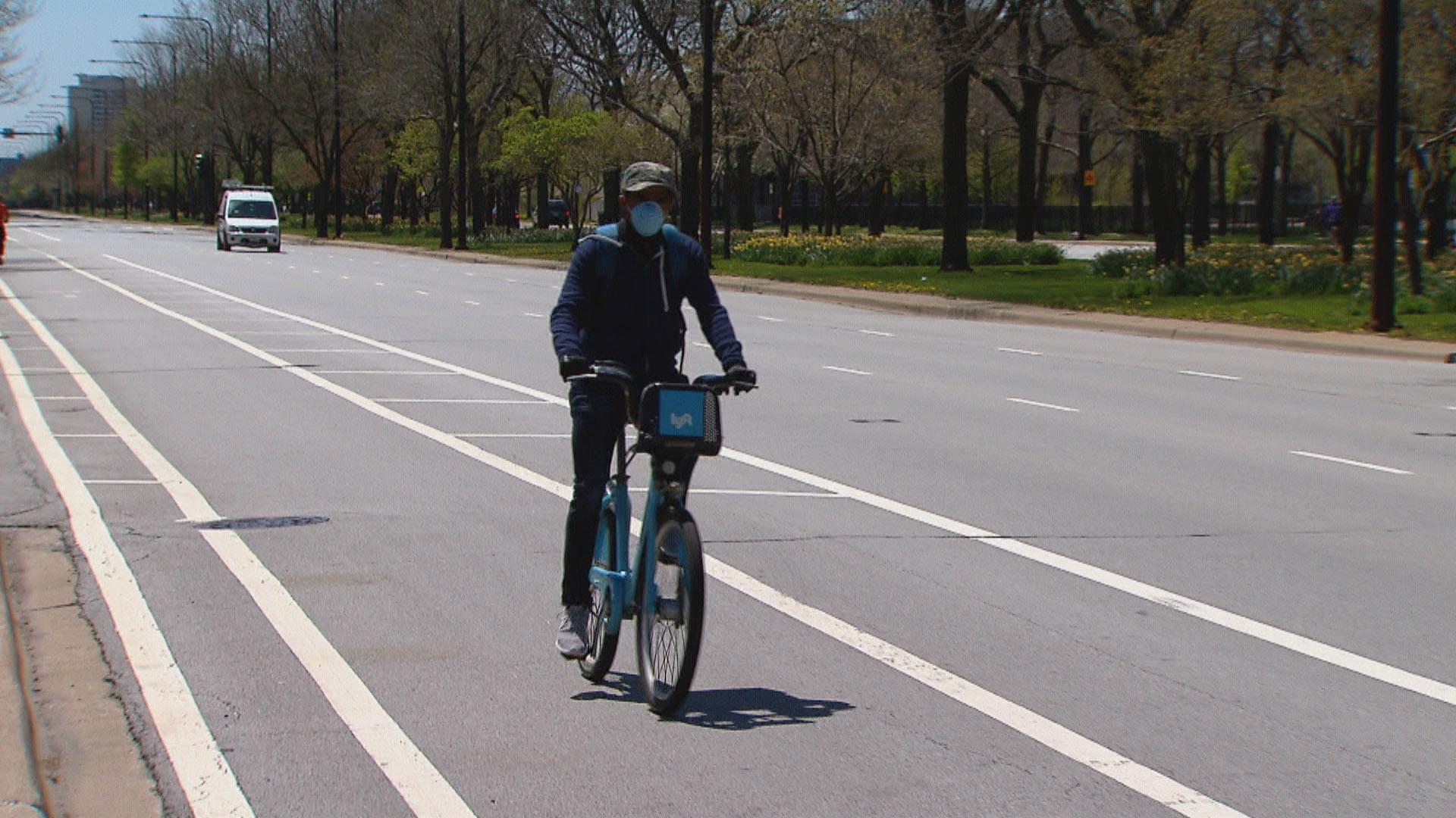 A cyclist wearing a face mask rides a Divvy bike in Chicago. (WTTW News)