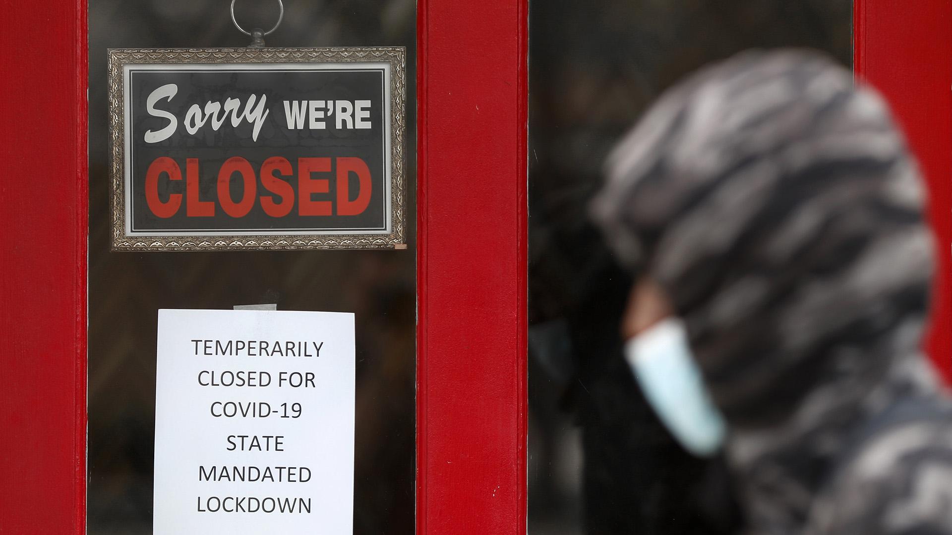 In this May 7, 2020, file photo, a pedestrian walks by The Framing Gallery, closed due to the COVID-19 pandemic, in Grosse Pointe, Michigan. (AP Photo / Paul Sancya, File)