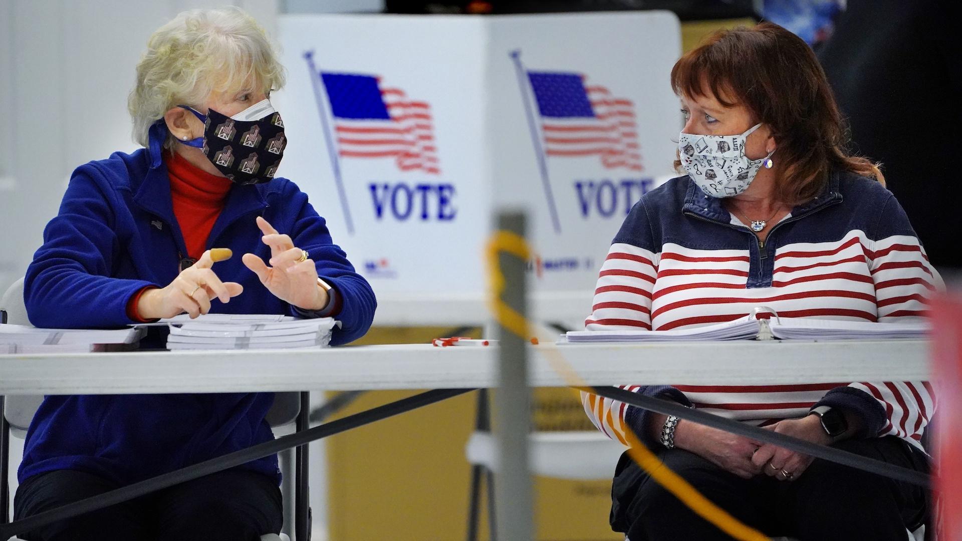 Election workers Sheila McDonough, left, and Kathleen Reid chat while waiting for voters at the American Legion Post 35 poling place, Tuesday, Nov. 2, 2021, in South Portland, Maine. (AP Photo/Robert F. Bukaty)