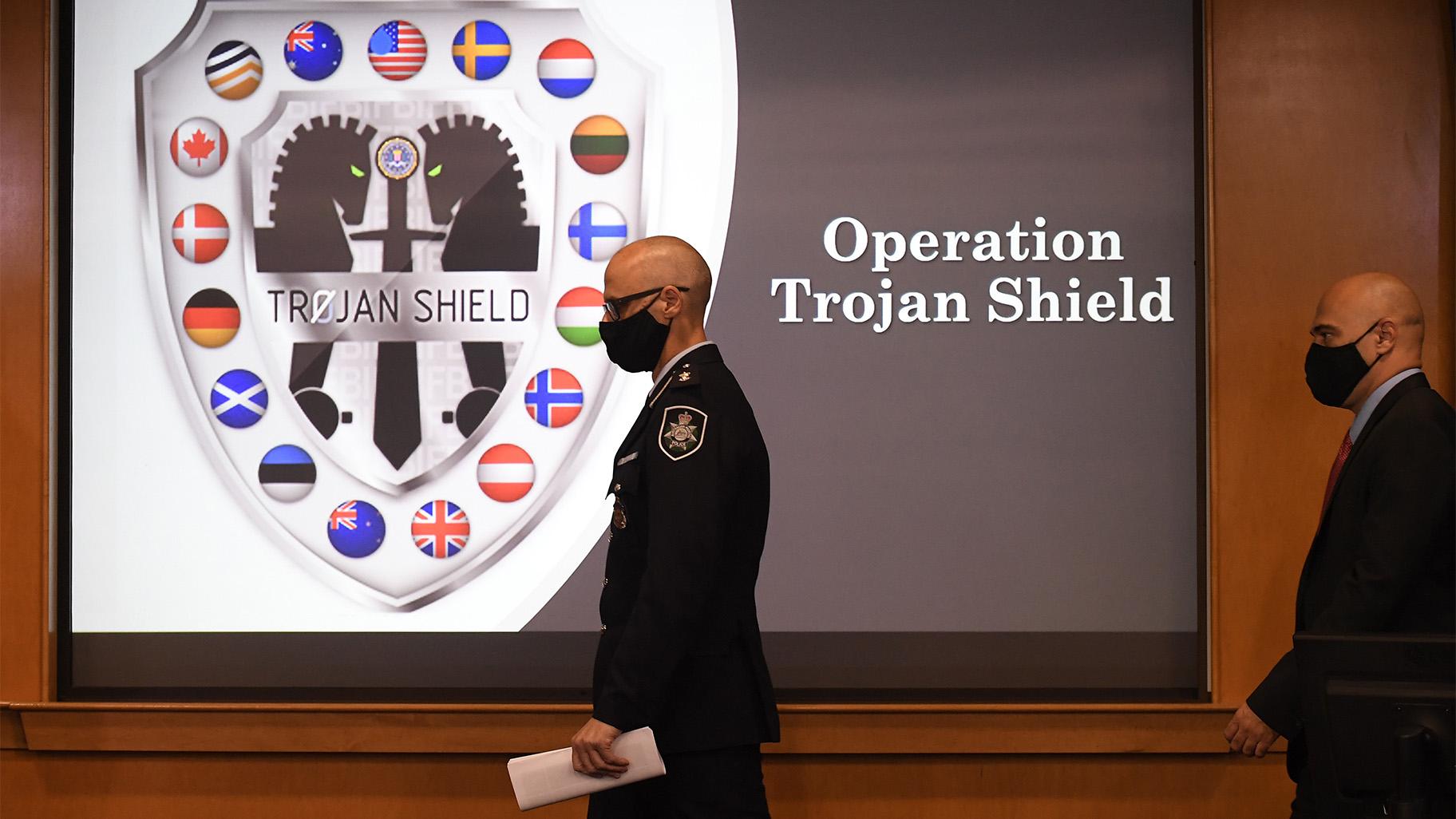 Law enforcement officials walk past an Operation Trojan Shield logo at a news conference, Tuesday, June 8, 2021, in San Diego. (AP Photo / Denis Poroy) 